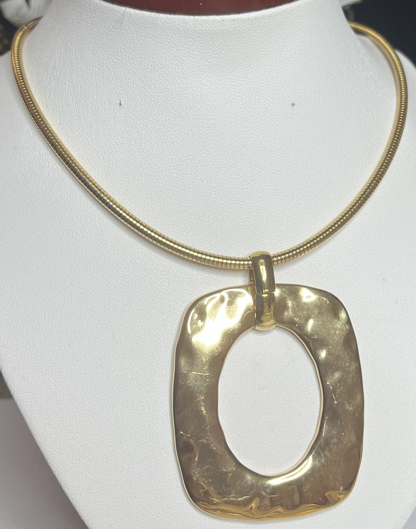 Collana Charlize in acciaio inossidabile placcato oro con catena a maglia serpente e pendente geometrico quadrato, esposta su busto bianco