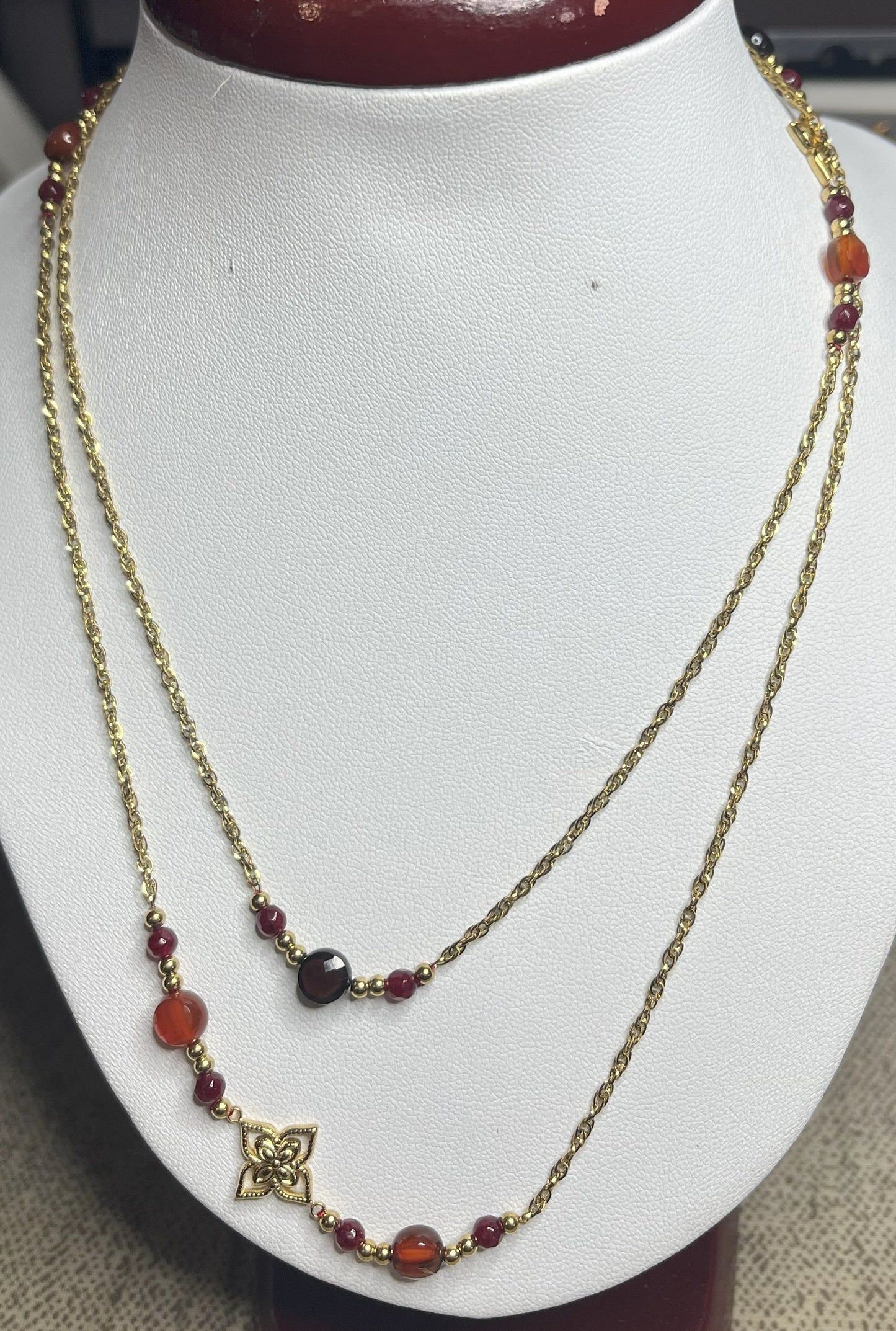 Collana doppio giro in acciaio inossidabile con pietre di agata rosse o verdi/azzurre ciondolo decorativo, esposta su busto bianco