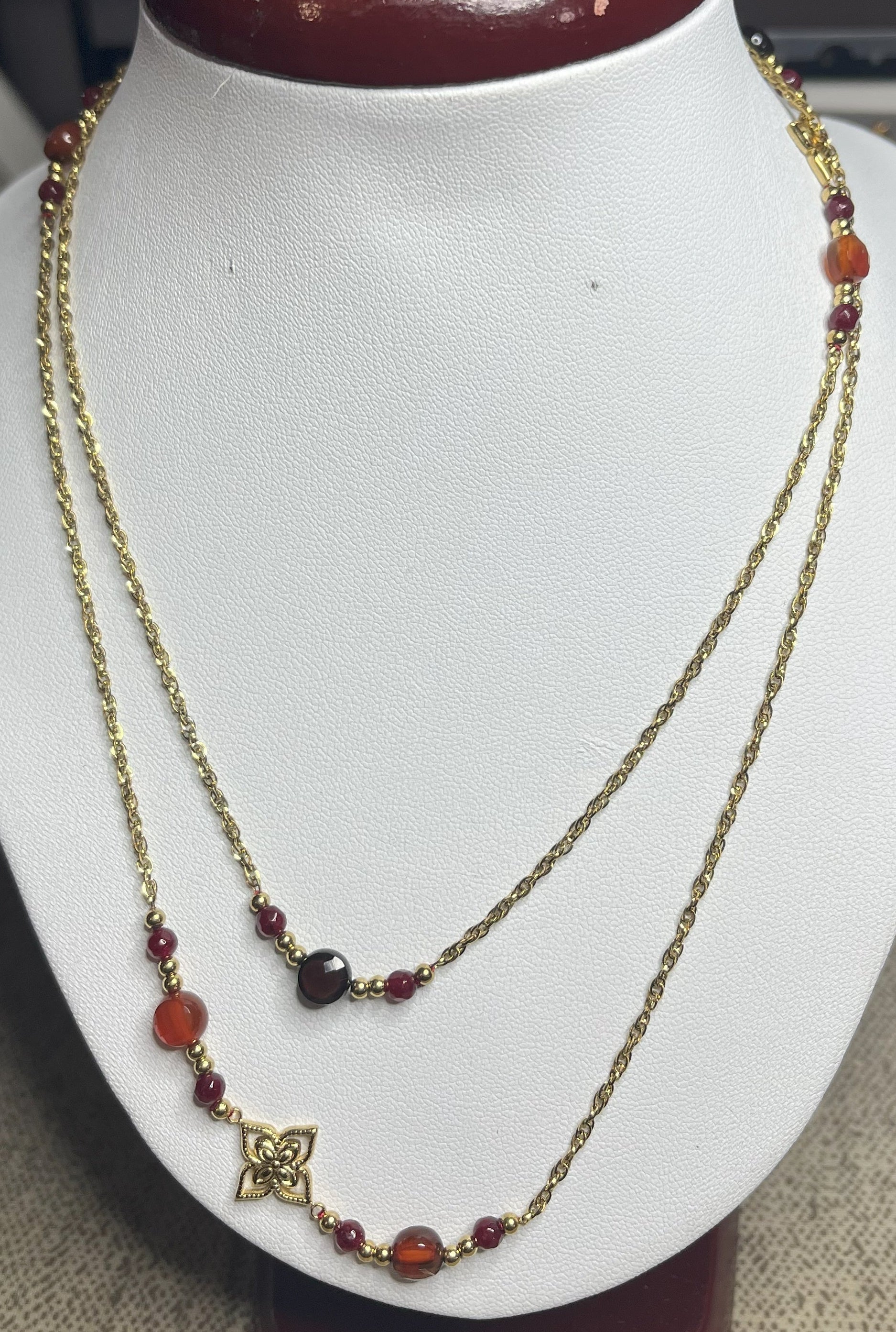 Collana doppio giro in acciaio inossidabile con pietre di agata rosse o verdi/azzurre ciondolo decorativo, esposta su busto bianco