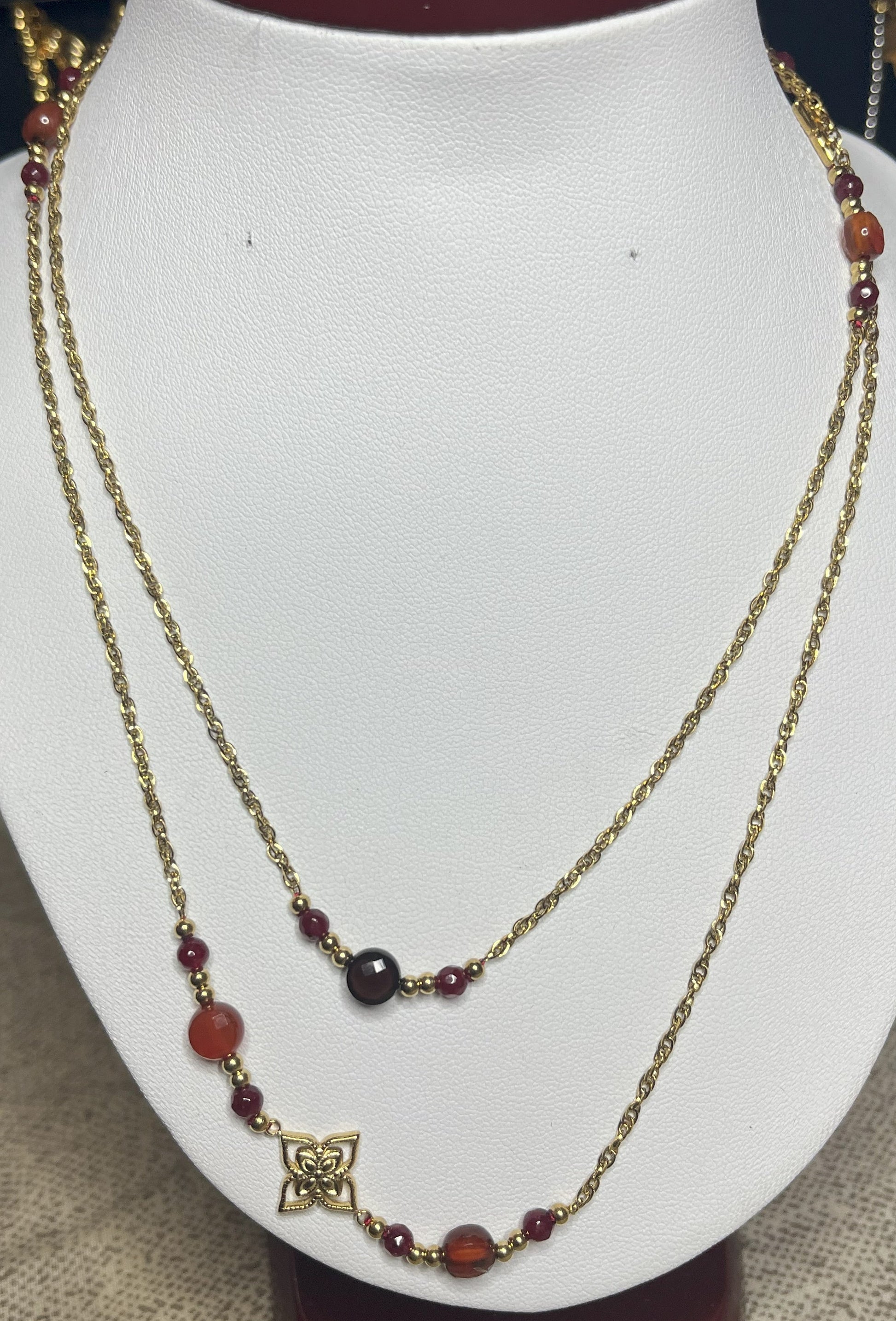 Collana doppio giro in acciaio inossidabile con pietre di agata rosse o verdi/azzurre ciondolo decorativo, esposta su busto bianco