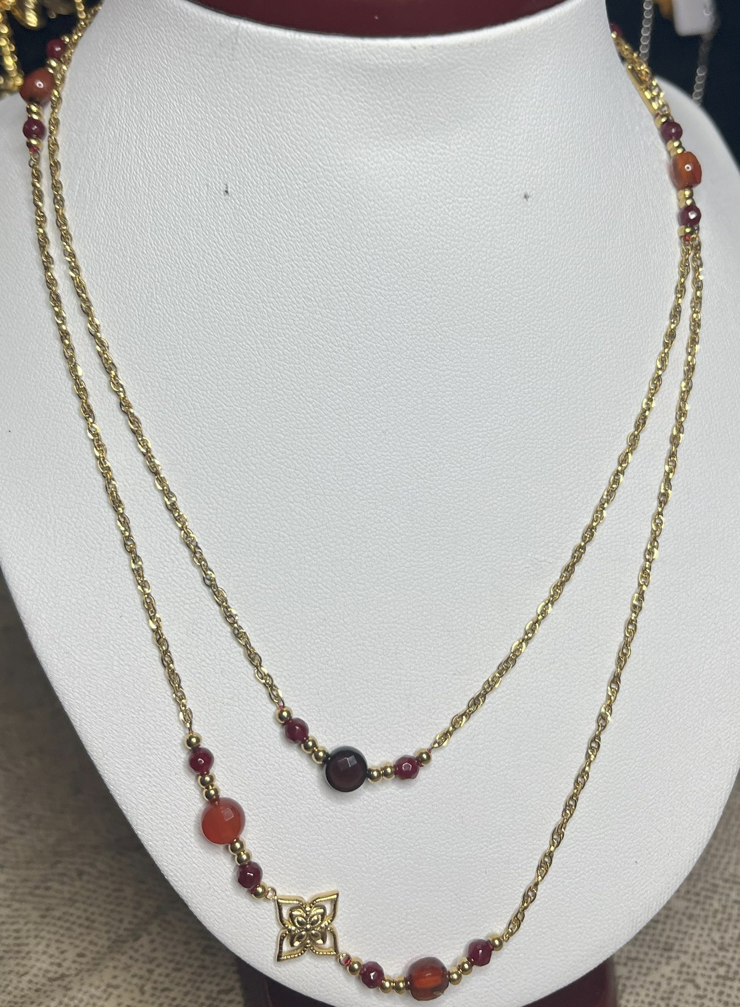 Collana doppio giro in acciaio inossidabile con pietre di agata rosse o verdi/azzurre ciondolo decorativo, esposta su busto bianco