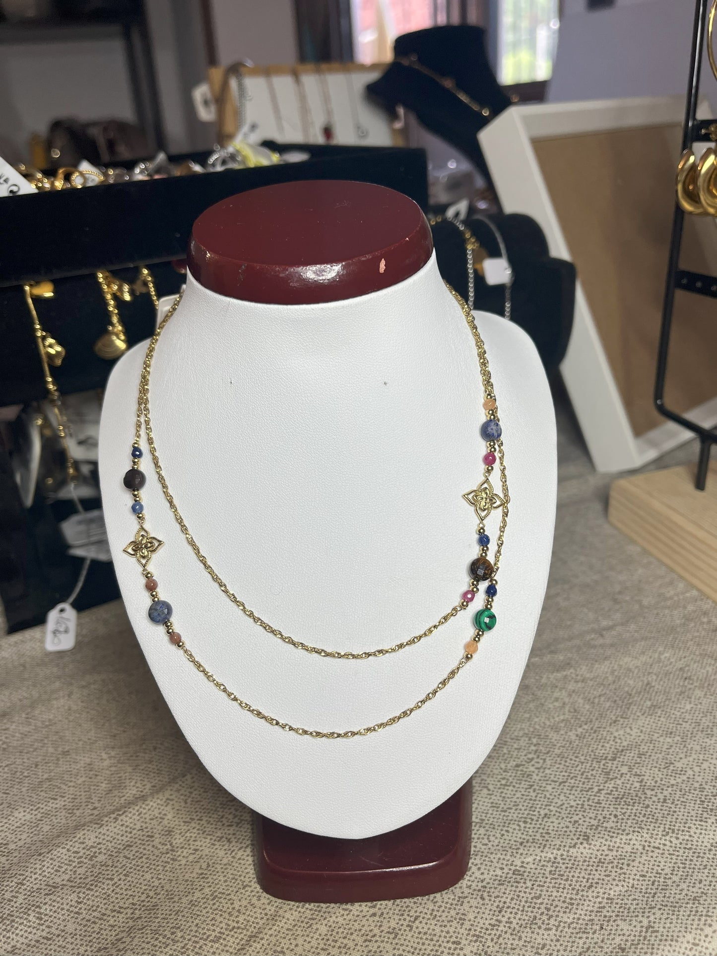 Collana doppio giro in acciaio inossidabile con pietre di agata rosse o verdi/azzurre ciondolo decorativo, esposta su busto bianco