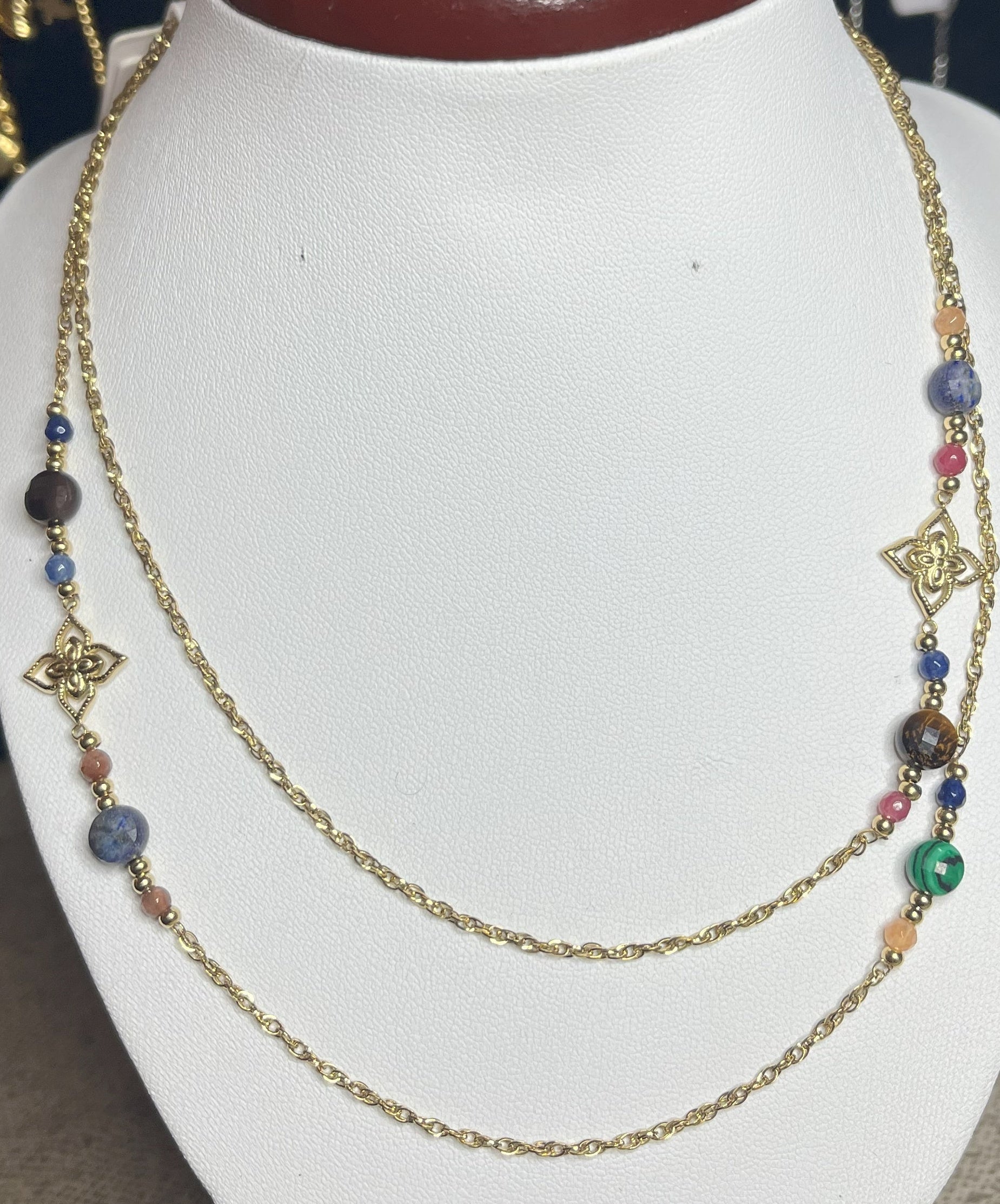 Collana doppio giro in acciaio inossidabile con pietre di agata rosse o verdi/azzurre ciondolo decorativo, esposta su busto bianco