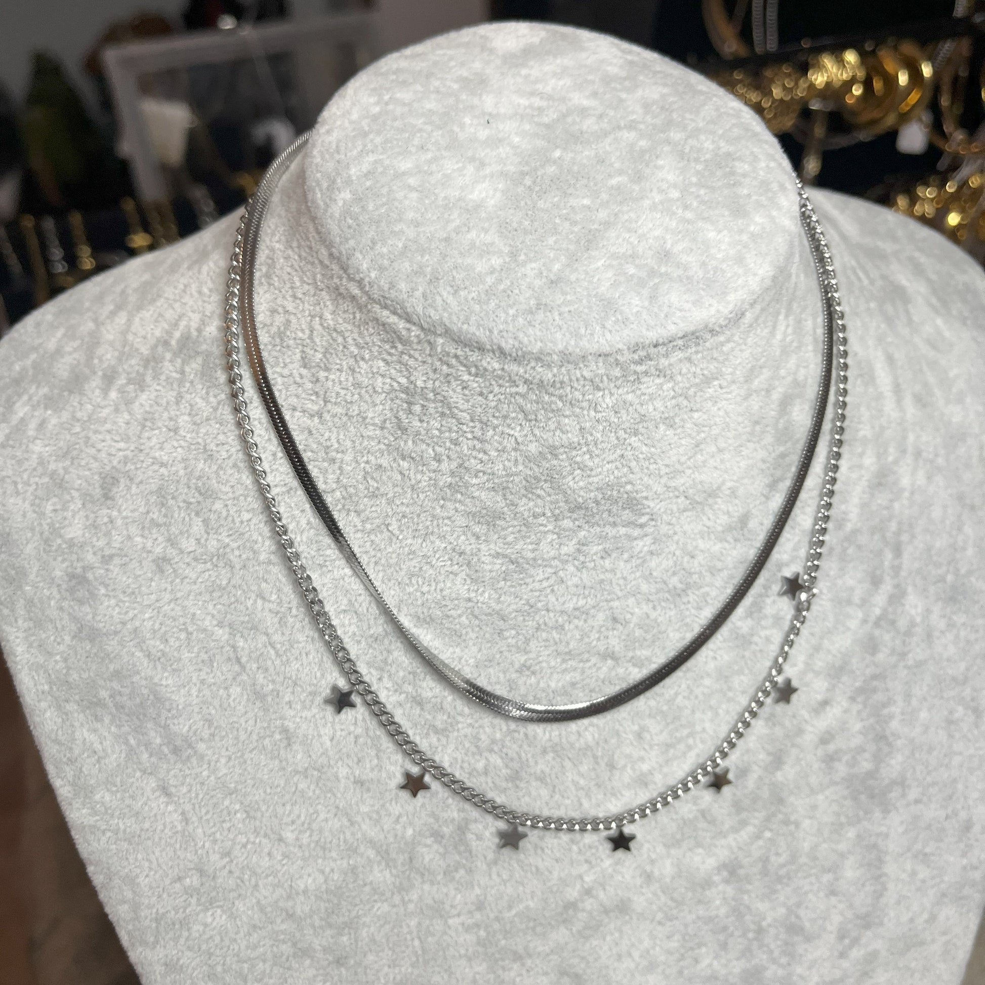 Collana Double Star in acciaio placcato argento con doppia catena layered, una snake liscia e una con stelle decorative, esposta su busto grigio