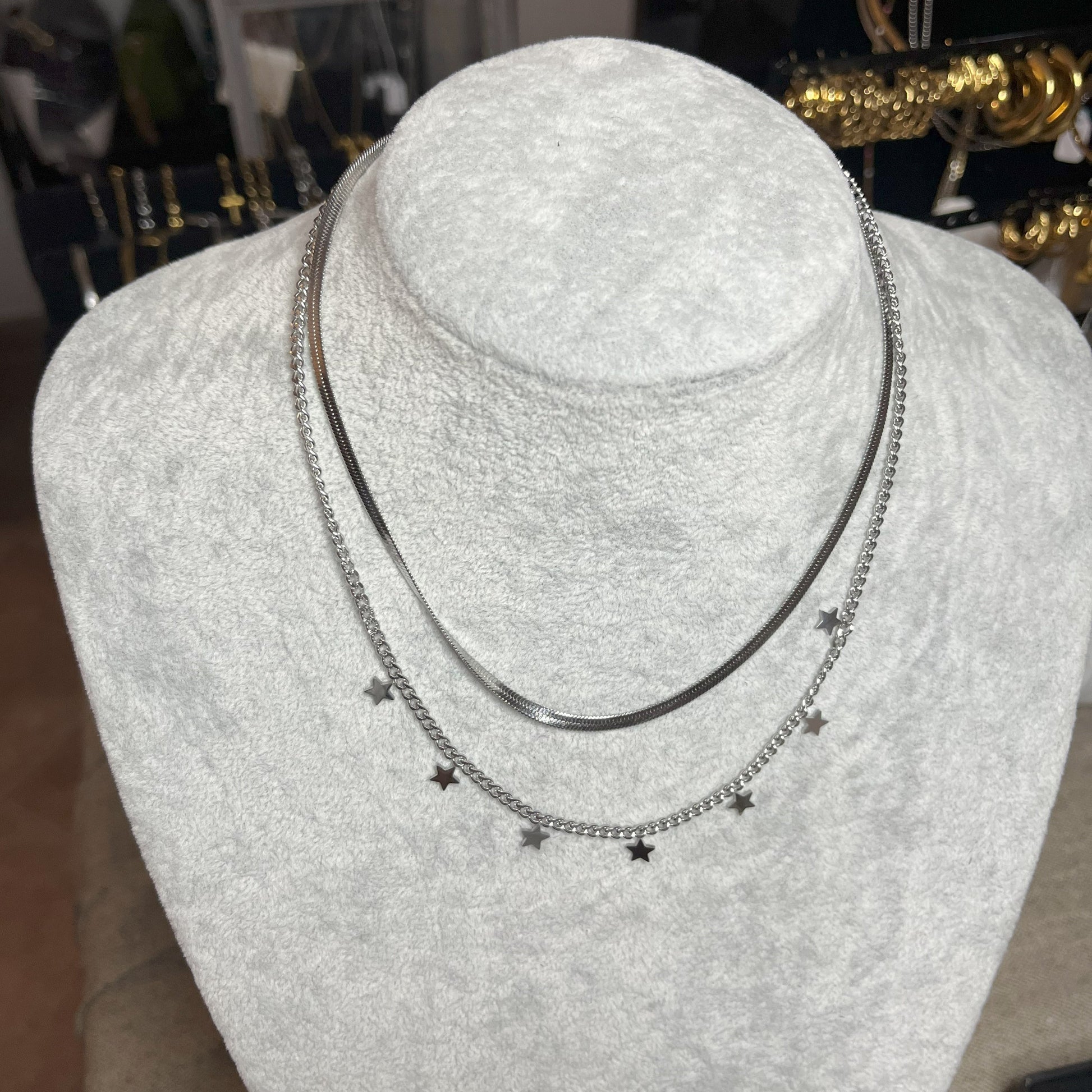 Collana Double Star in acciaio placcato argento con doppia catena layered, una snake liscia e una con stelle decorative, esposta su busto grigio