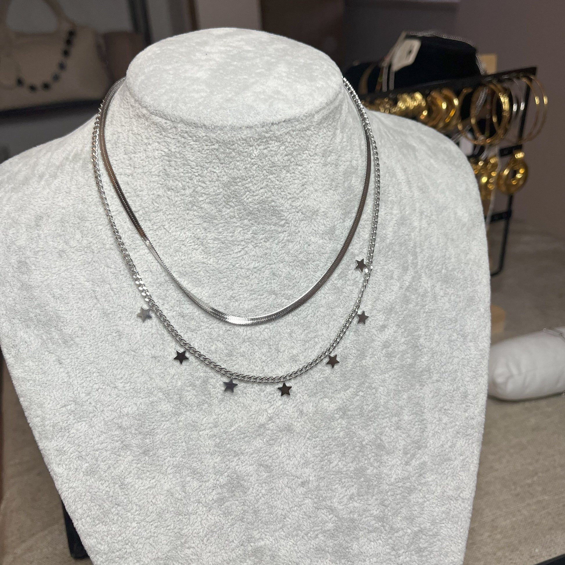 Collana Double Star in acciaio placcato argento con doppia catena layered, una snake liscia e una con stelle decorative, esposta su busto grigio