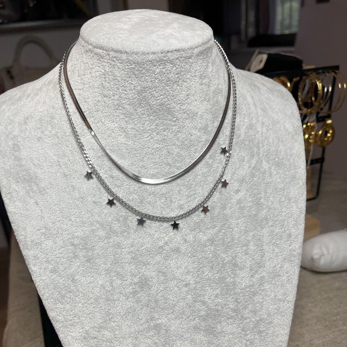 Collana Double Star in acciaio placcato argento con doppia catena layered, una snake liscia e una con stelle decorative, esposta su busto grigio