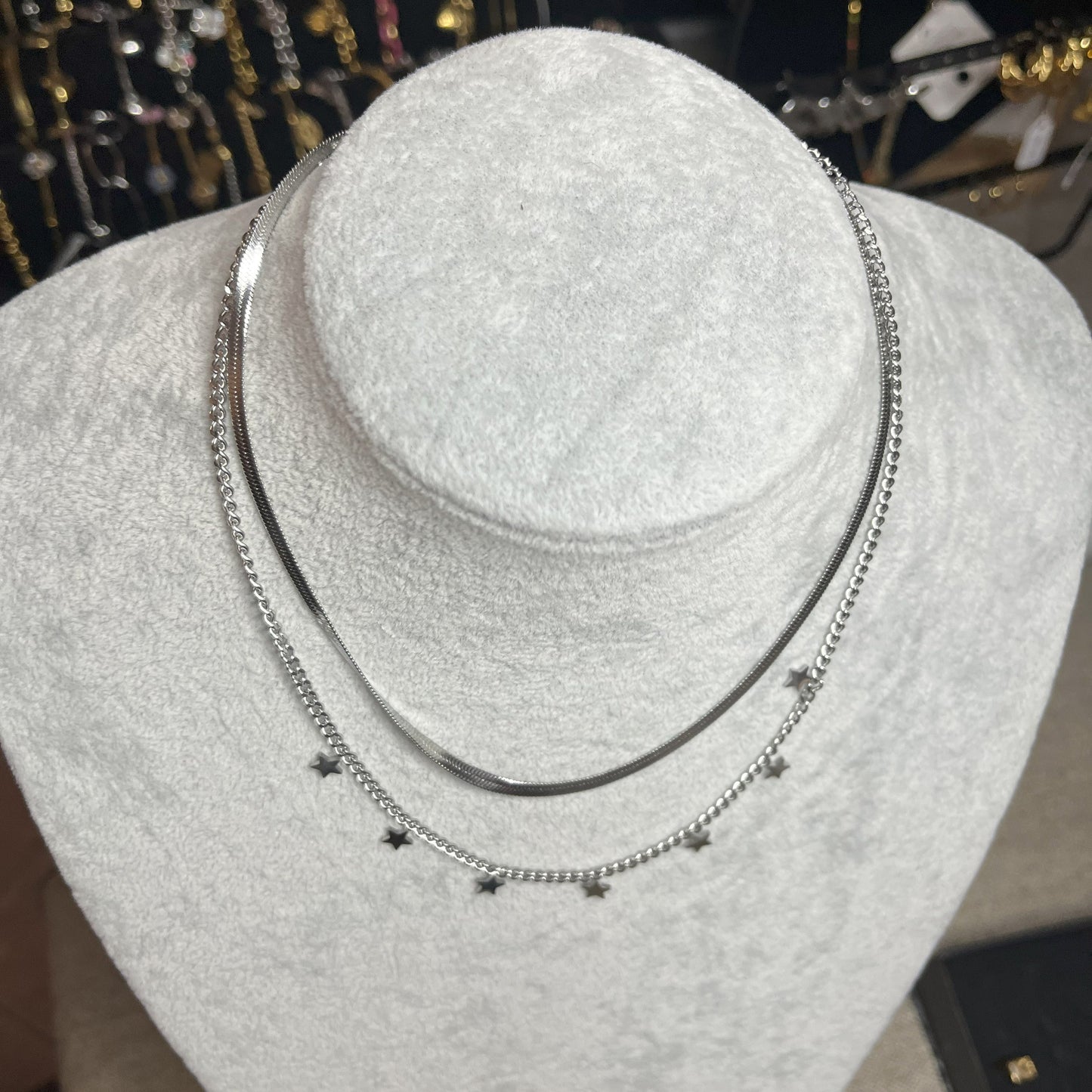 Collana Double Star in acciaio placcato argento con doppia catena layered, una snake liscia e una con stelle decorative, esposta su busto grigio