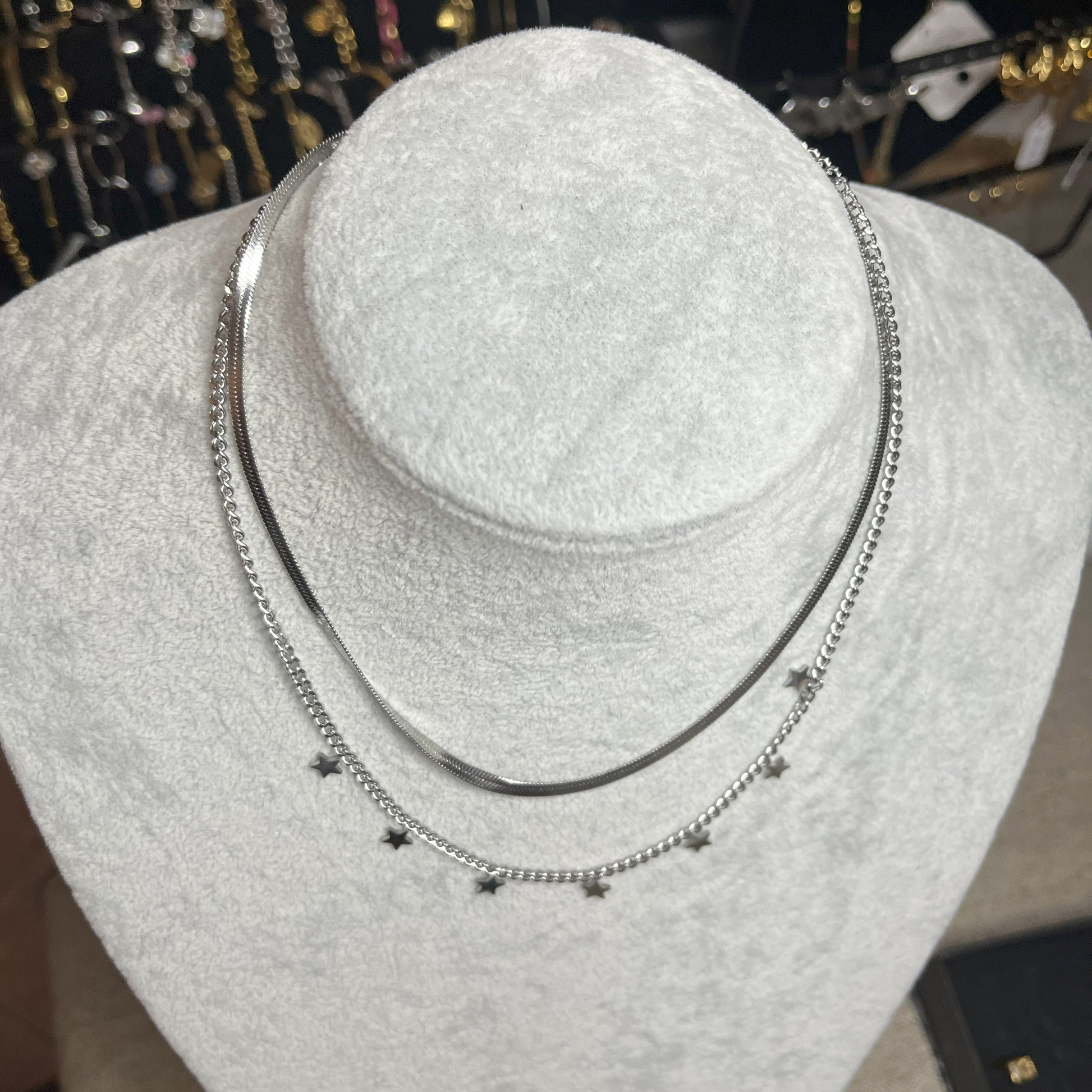 Collana Double Star in acciaio placcato argento con doppia catena layered, una snake liscia e una con stelle decorative, esposta su busto grigio