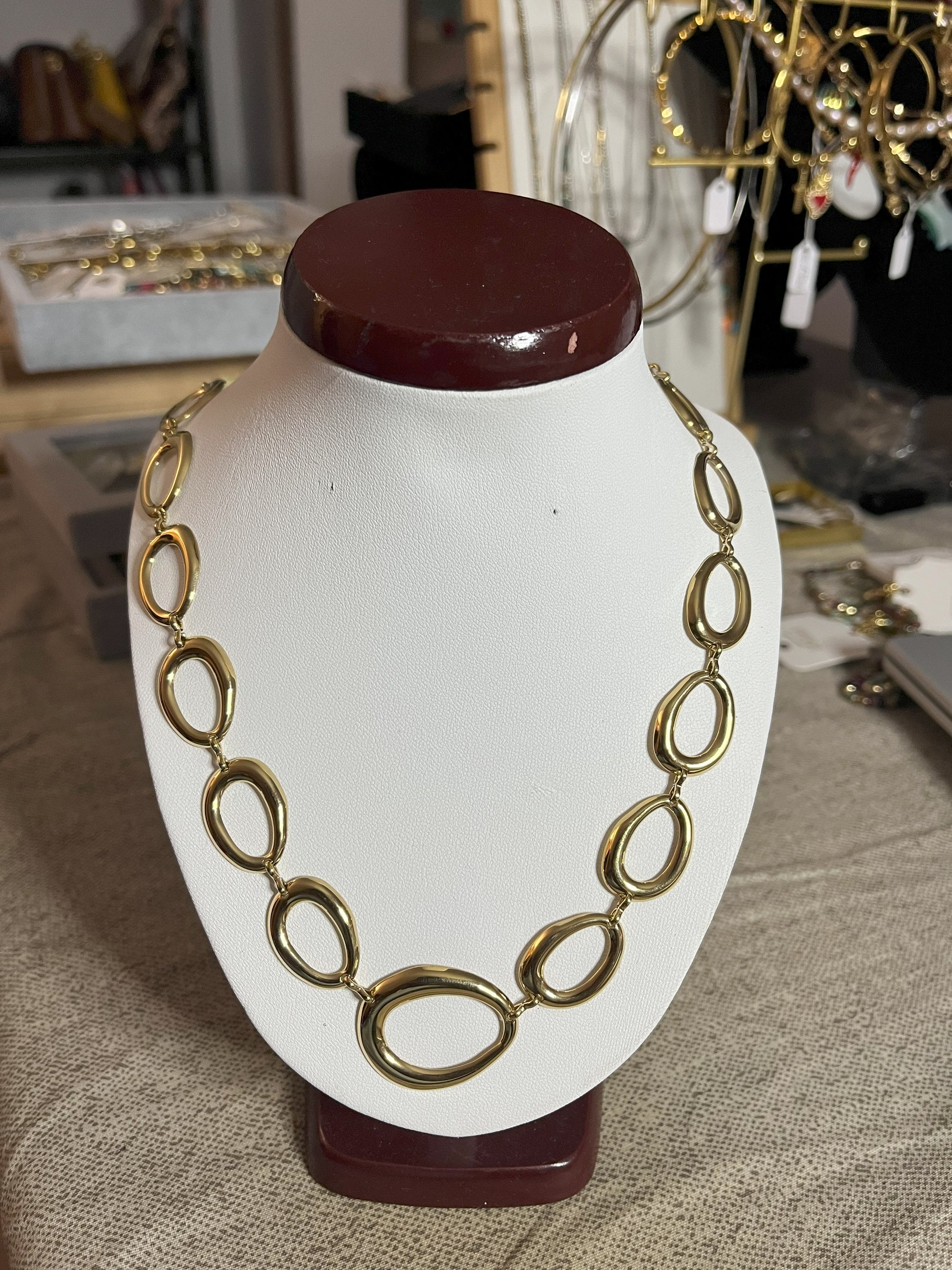 Collana Golden Embrace con anelli ovali dorati concatenati placcati oro su espositore bianco, design elegante statement per donna