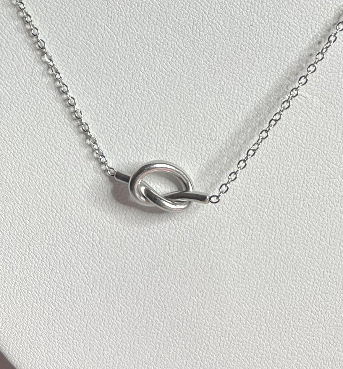 Collana Love Knot con pendente a nodo intrecciato dorato su catena delicata, dettaglio nodo