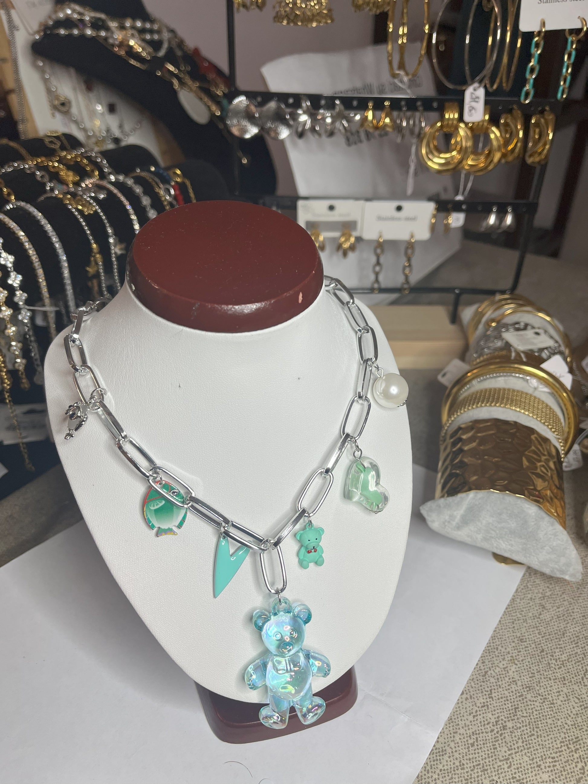 Collana chunky in alluminio trattato con orsetto turchese e pendenti verdi esposta su busto bianco