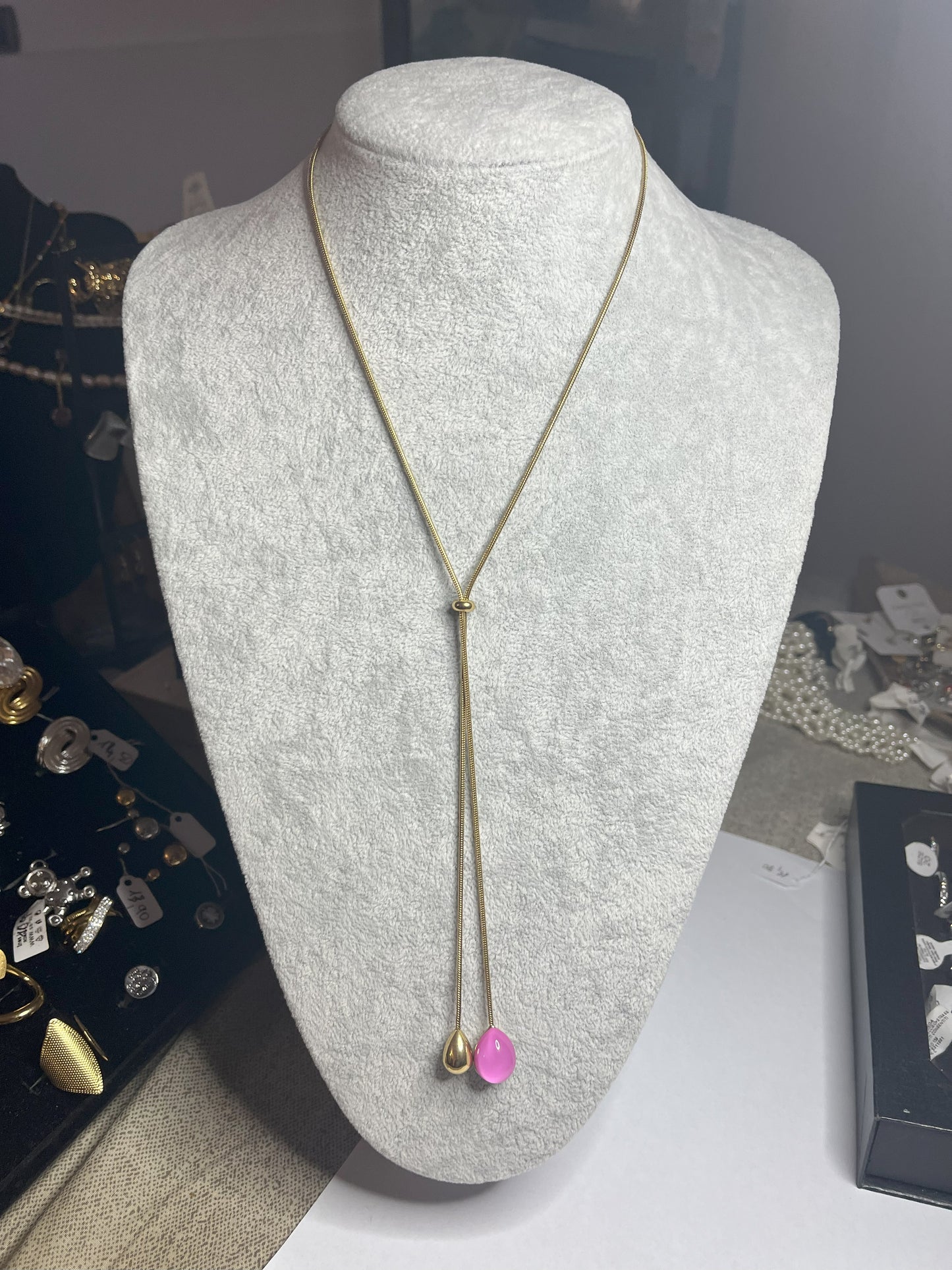 Collana Saliscendi Punto Fucsia in acciaio premium placcato oro con catena regolabile e terminale fucsia vibrante, esposta su busto grigio