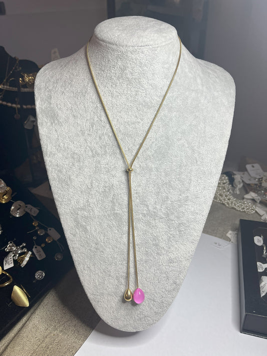Collana Saliscendi Punto Fucsia in acciaio premium placcato oro con catena regolabile e terminale fucsia vibrante, esposta su busto grigio