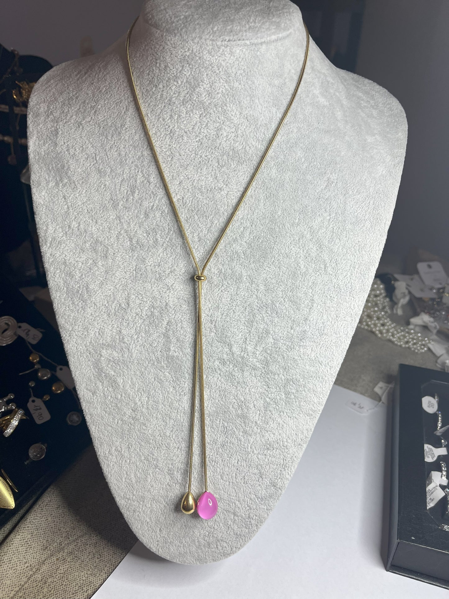 Collana Saliscendi Punto Fucsia in acciaio premium placcato oro con catena regolabile e terminale fucsia vibrante, esposta su busto grigio