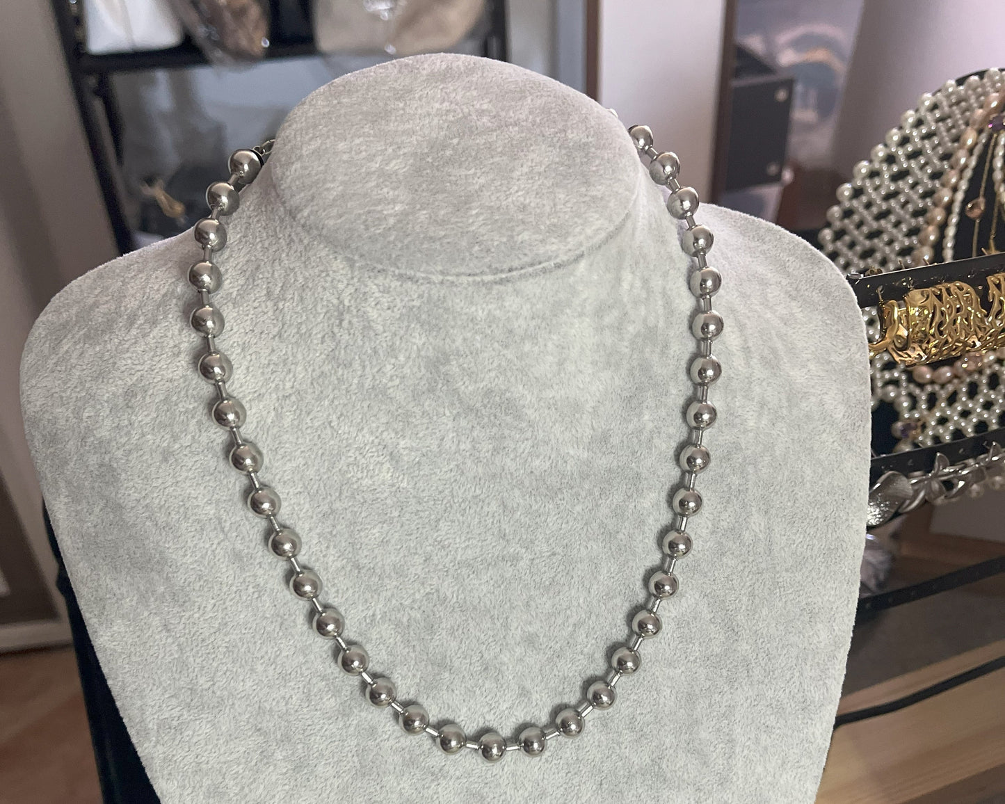 Collana Sfere in acciaio inox placcato argento con sfere metalliche uniformi, esposta su busto grigio chiaro