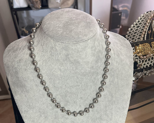 Collana Sfere in acciaio inox placcato argento con sfere metalliche uniformi, esposta su busto grigio chiaro