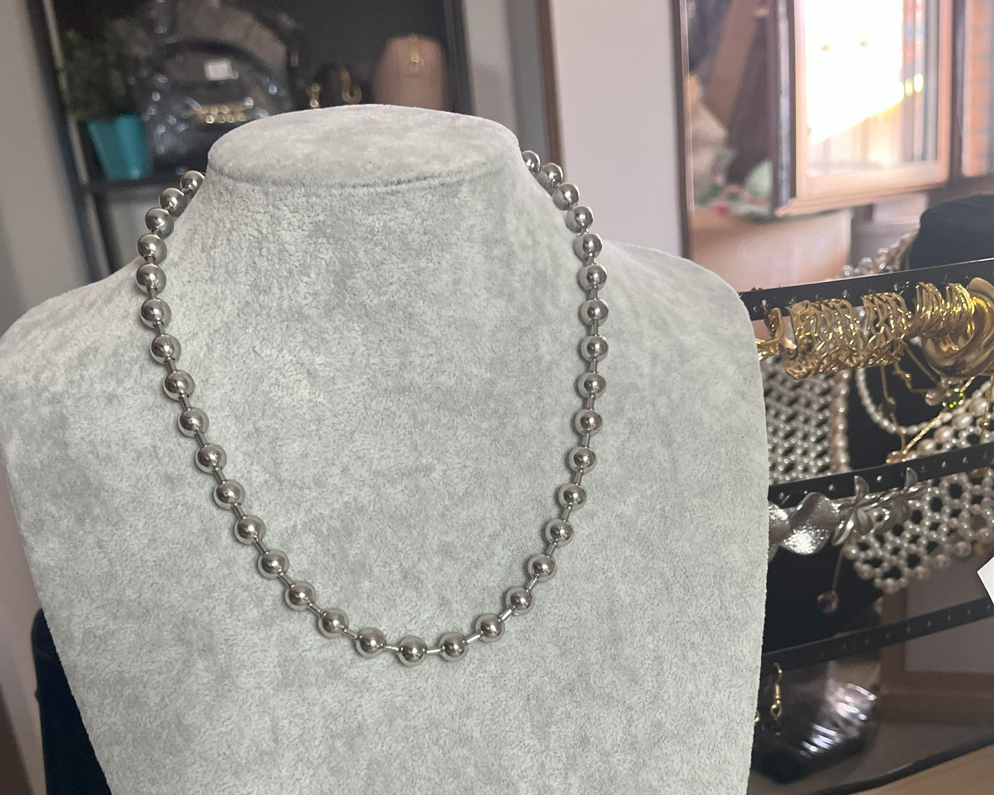 Collana Sfere in acciaio inox placcato argento con sfere metalliche uniformi, esposta su busto grigio chiaro