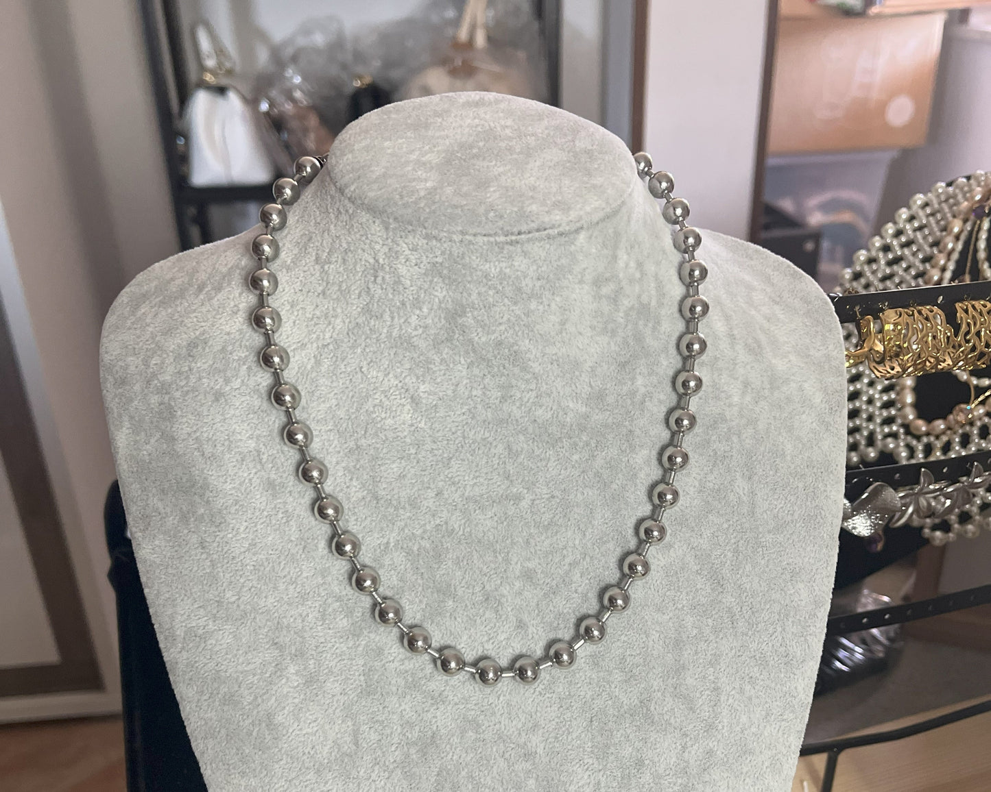 Collana Sfere in acciaio inox placcato argento con sfere metalliche uniformi, esposta su busto grigio chiaro