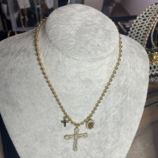 Collana Sfere Croce in acciaio premium placcato oro con catena a sfere e ciondolo croce decorato, esposta su busto grigio