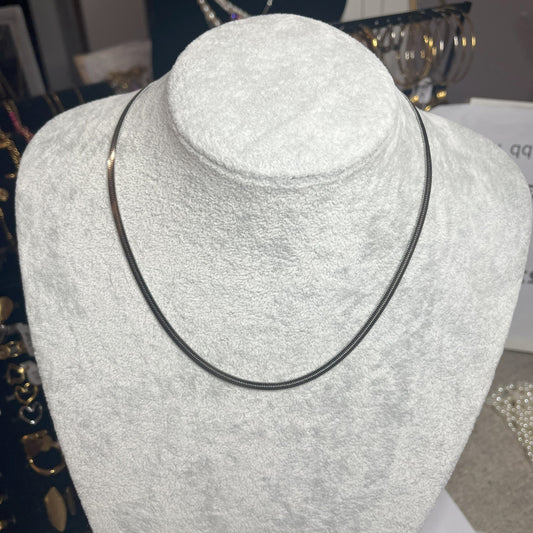 Collana Snake in acciaio premium in placcatura argento, con design ultra-sottile fluido, esposta su busto grigio chiaro