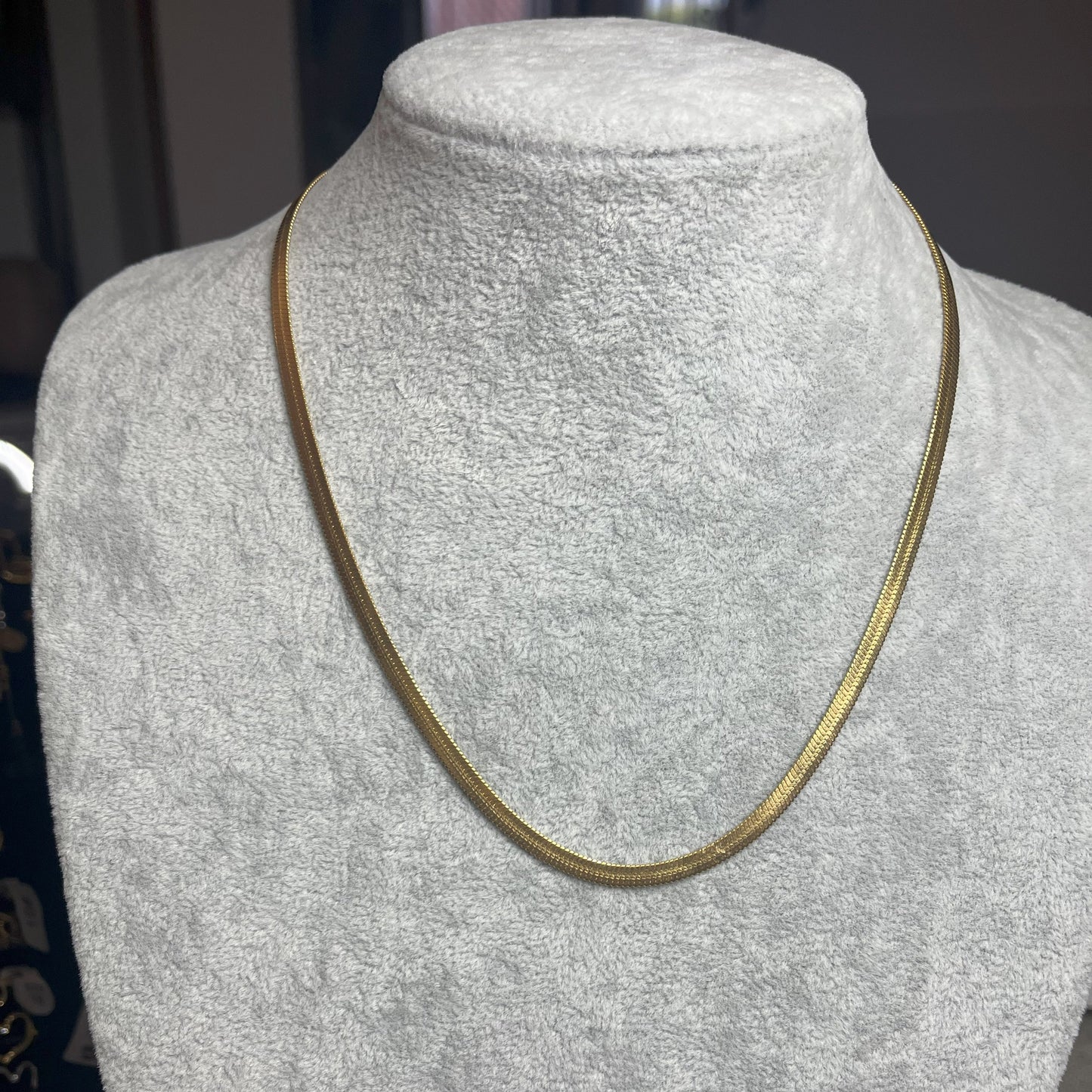Collana Snake in acciaio premium in placcatura argento, con design ultra-sottile fluido, esposta su busto grigio chiaro
