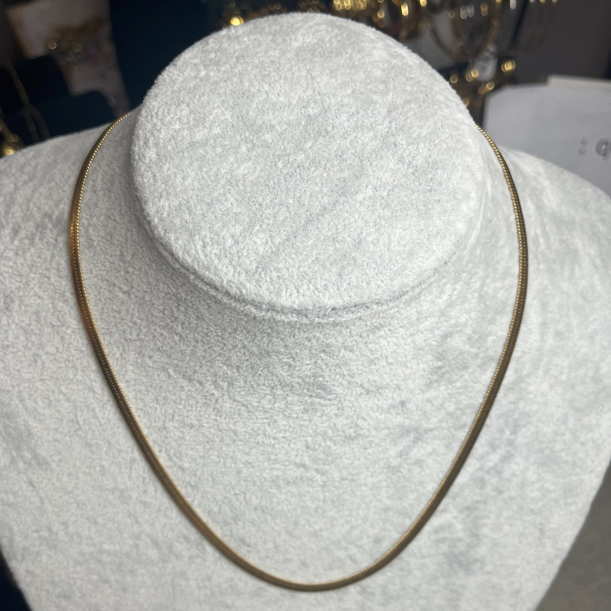 Collana Snake in acciaio premium in placcatura argento, con design ultra-sottile fluido, esposta su busto grigio chiaro