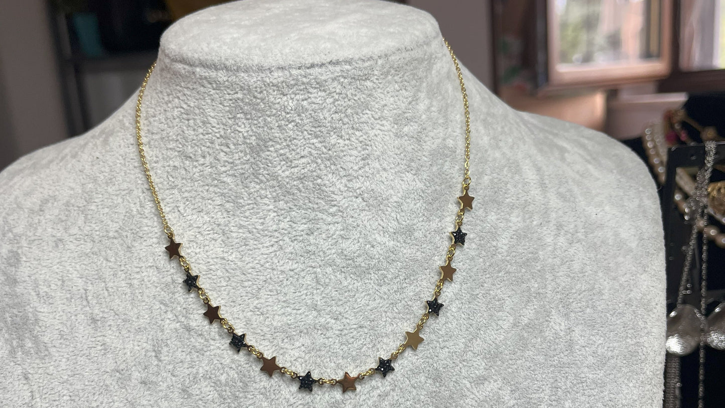 Collana Stelline Dorate - elegante catena dorata con piccole stelle nere alternate, gioiello minimalista su busto espositore