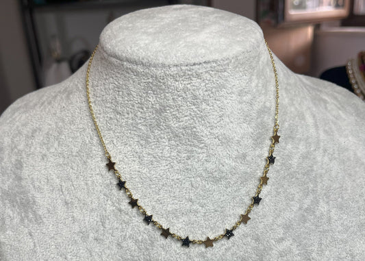 Collana Stelline Dorate - elegante catena dorata con piccole stelle nere alternate, gioiello minimalista su busto espositore