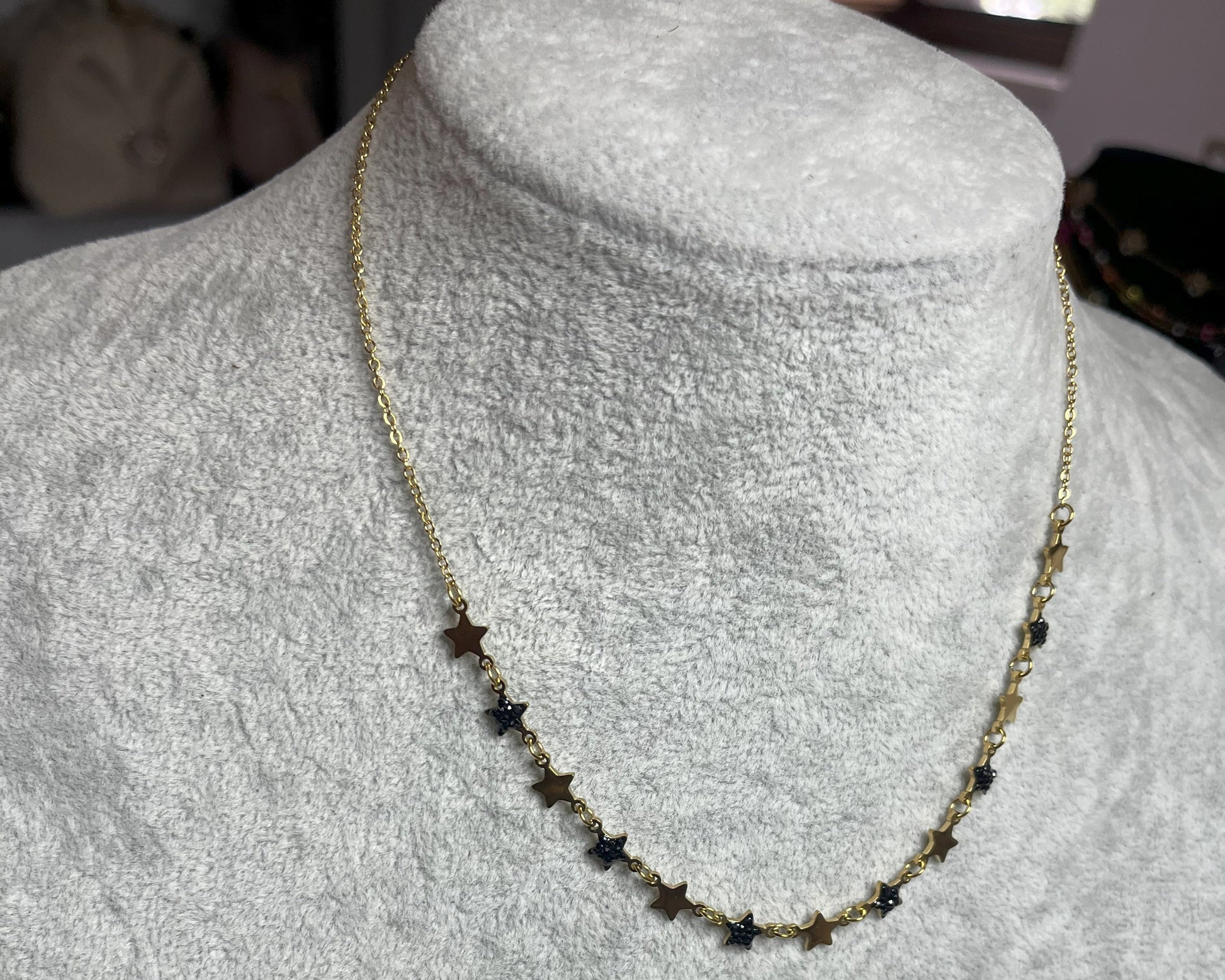Collana Stelline Dorate - elegante catena dorata con piccole stelle nere alternate, gioiello minimalista su busto espositore