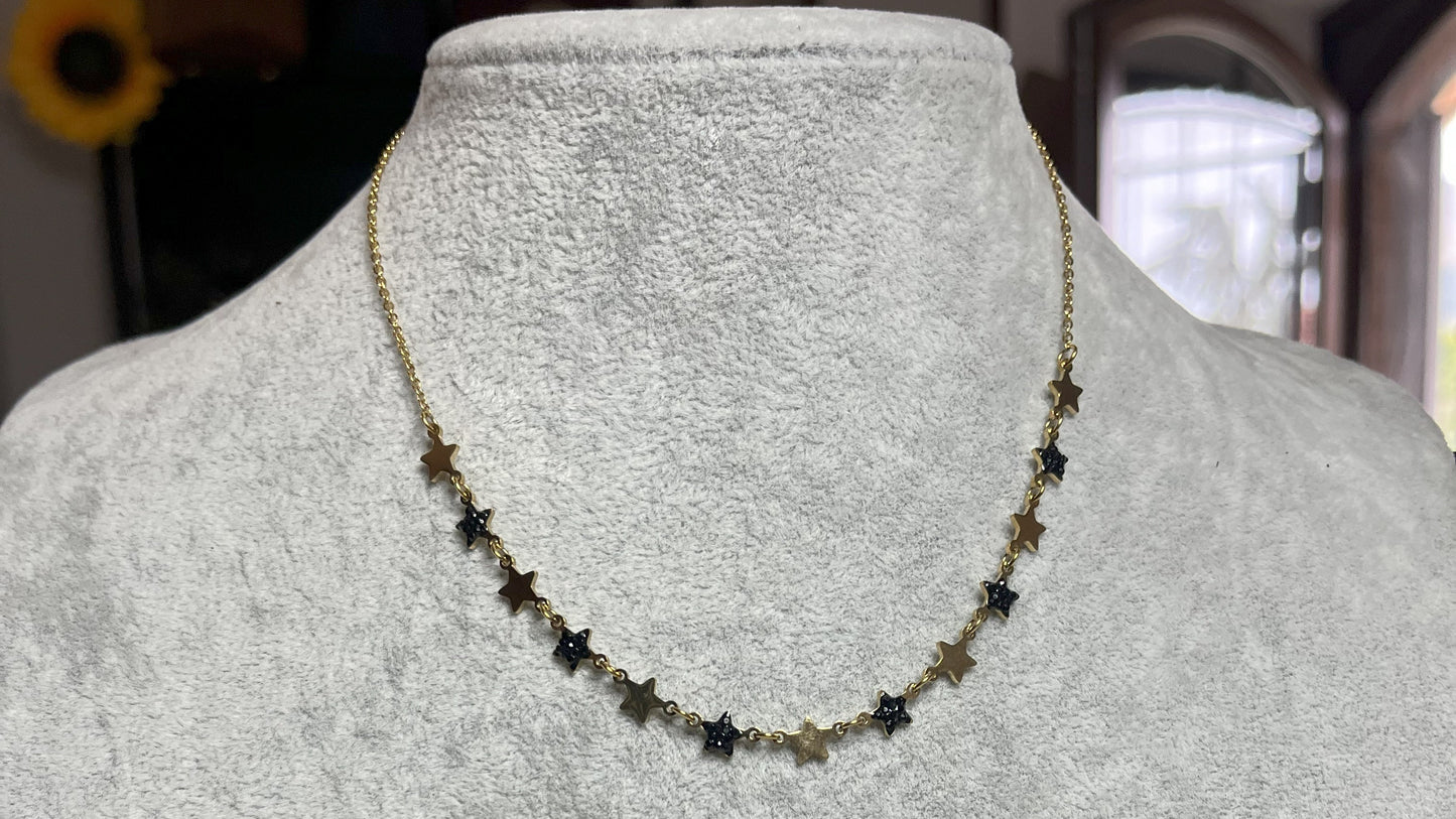Collana Stelline Dorate - elegante catena dorata con piccole stelle nere alternate, gioiello minimalista su busto espositore