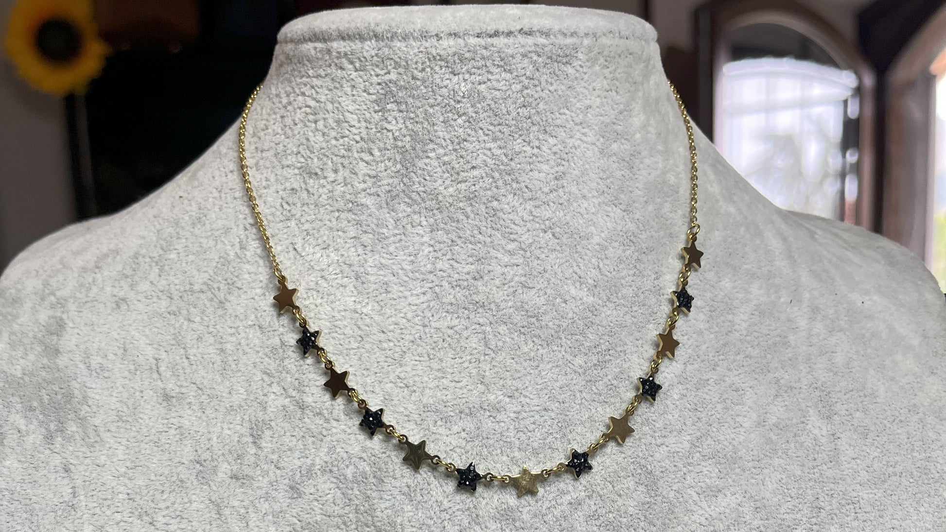Collana Stelline Dorate - elegante catena dorata con piccole stelle nere alternate, gioiello minimalista su busto espositore