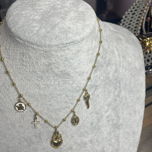 Collana Zoe Charms con Angelo in acciaio premium placcato oro con ciondoli multipli e charm angelo, indossata su busto espositore grigio