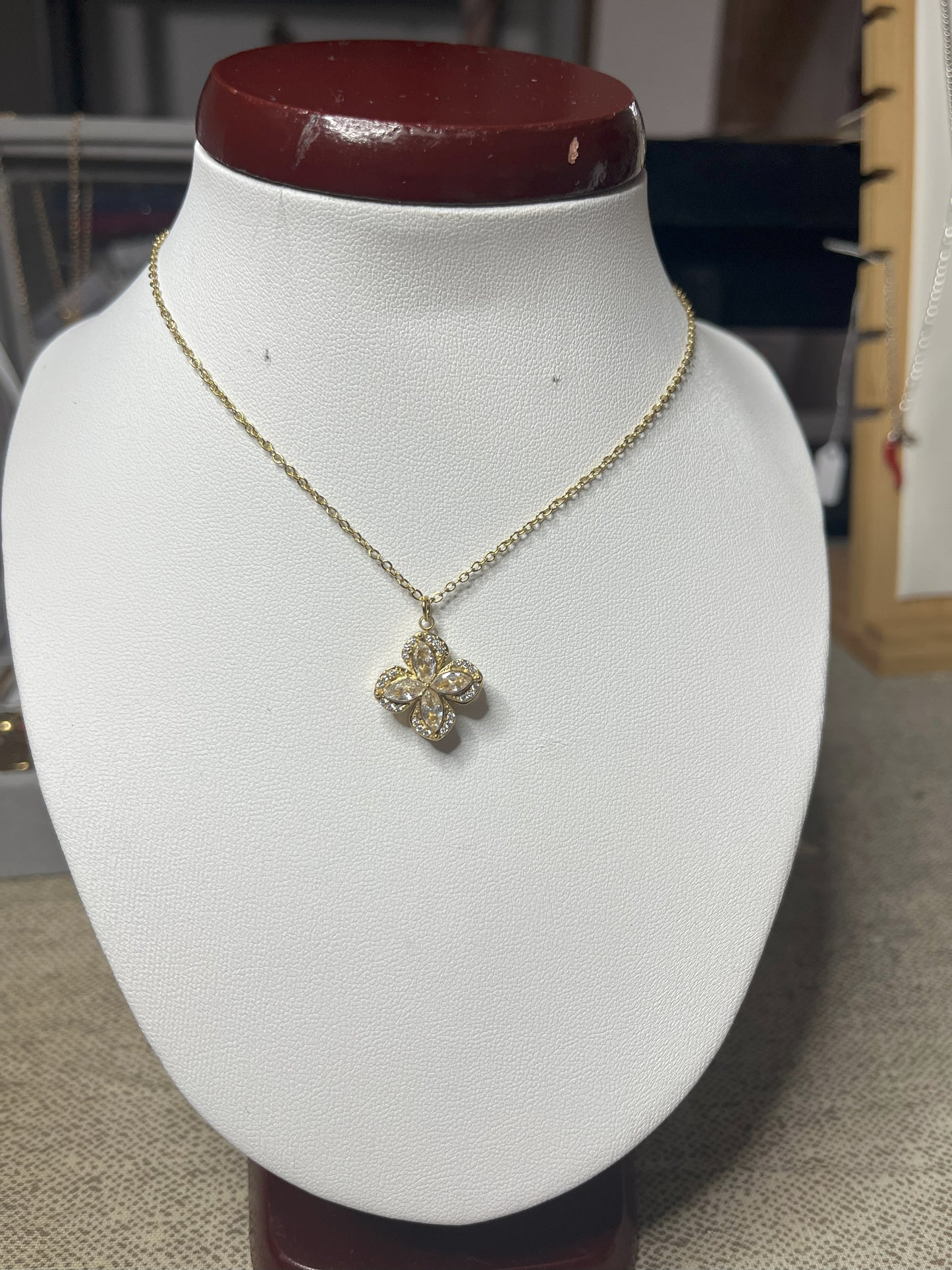 Collana in acciaio con ciondolo quadrifoglio decorato con zirconi su busto espositore bianco con base rossa