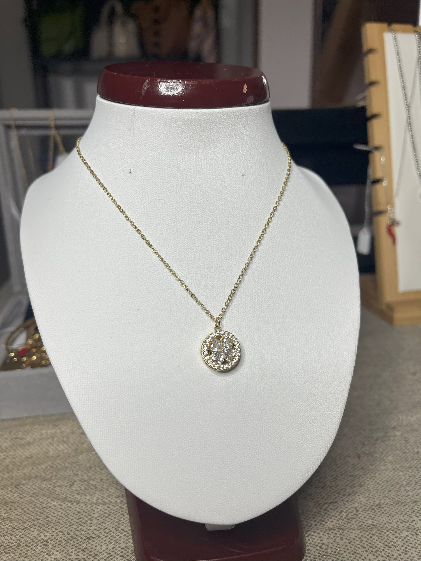 Collana Wish con elegante ciondolo quadrifoglio dorato e dettagli scintillanti, esposta su busto porta gioielli bianco