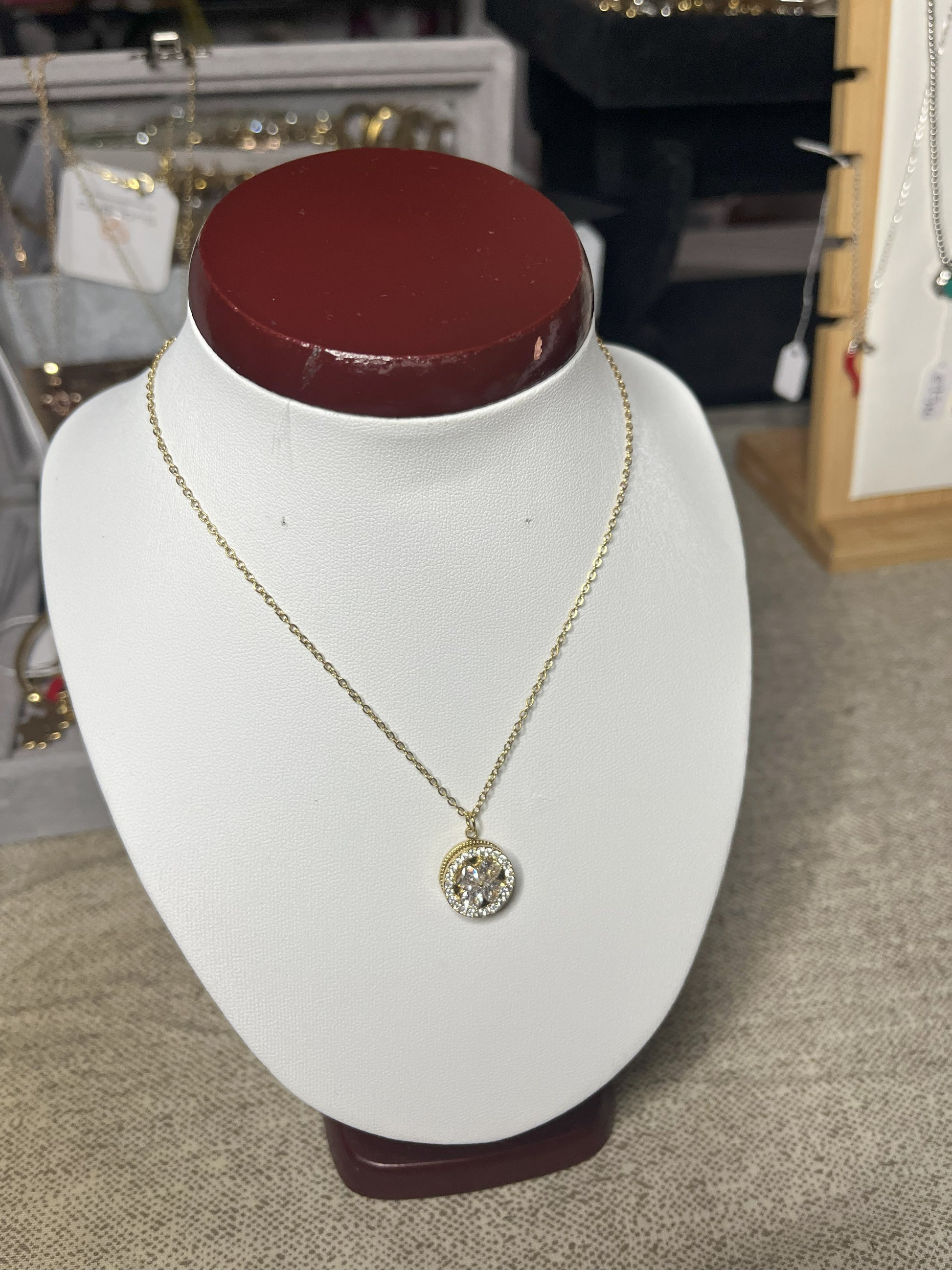 Collana Wish con elegante ciondolo quadrifoglio dorato e dettagli scintillanti, esposta su busto porta gioielli bianco