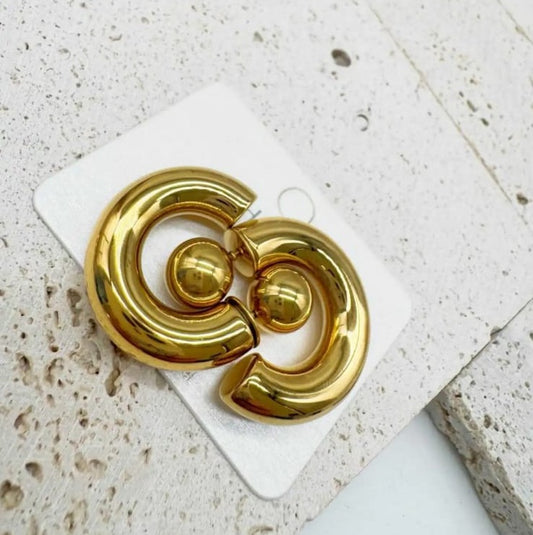 recchini Earcuff premium placcati oro con design curvo a C avvolgente, fotografati su superficie marmorizzata bianca