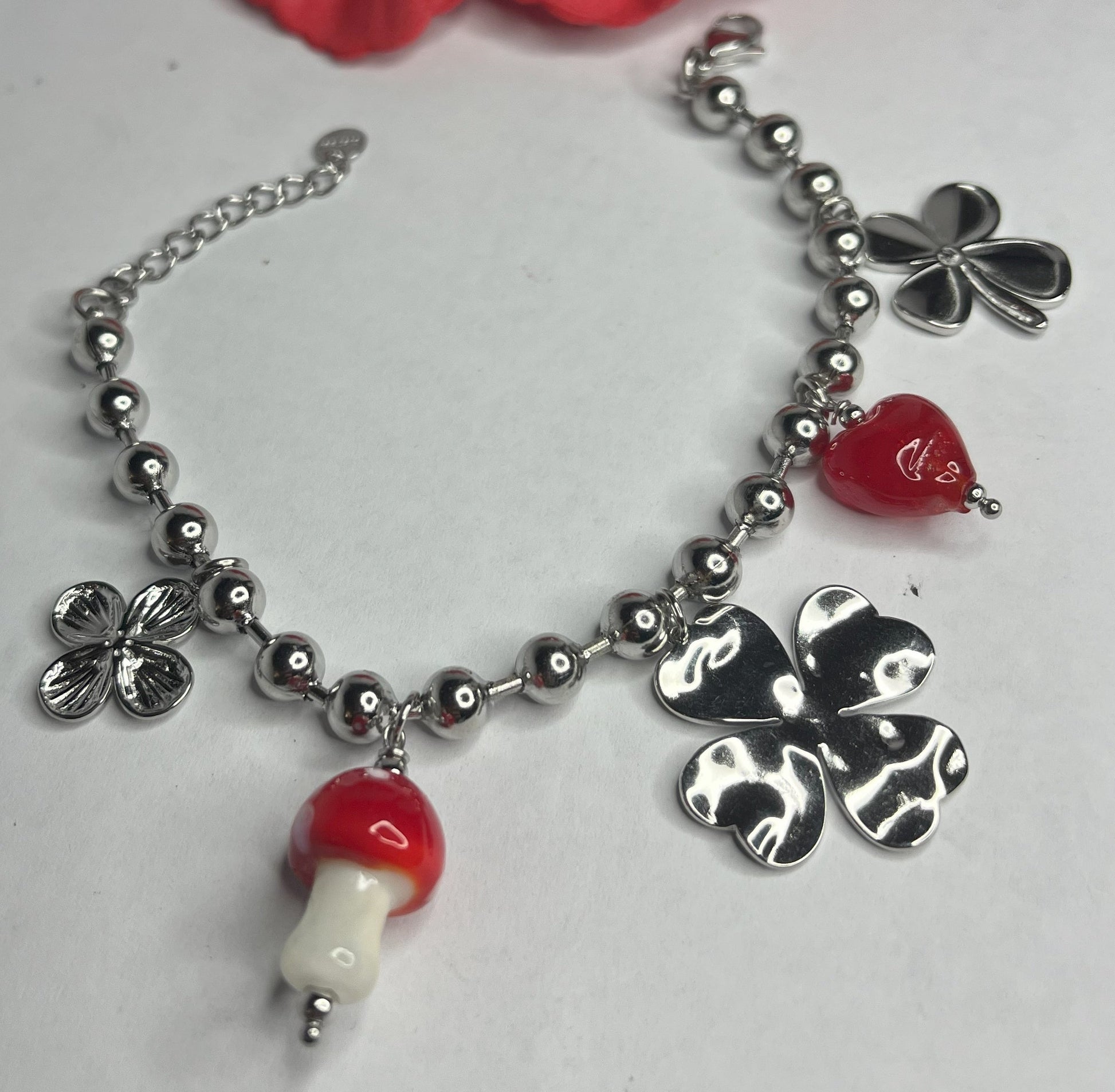 Braccialetto Giardino Magico in acciaio inox argentato con charms floreali, cuori rossi e perline colorate su sfondo grigio
