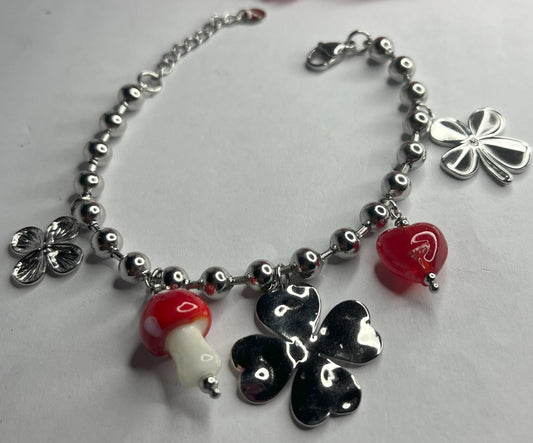 Braccialetto Giardino Magico in acciaio inox argentato con charms floreali, cuori rossi e perline colorate su sfondo grigio