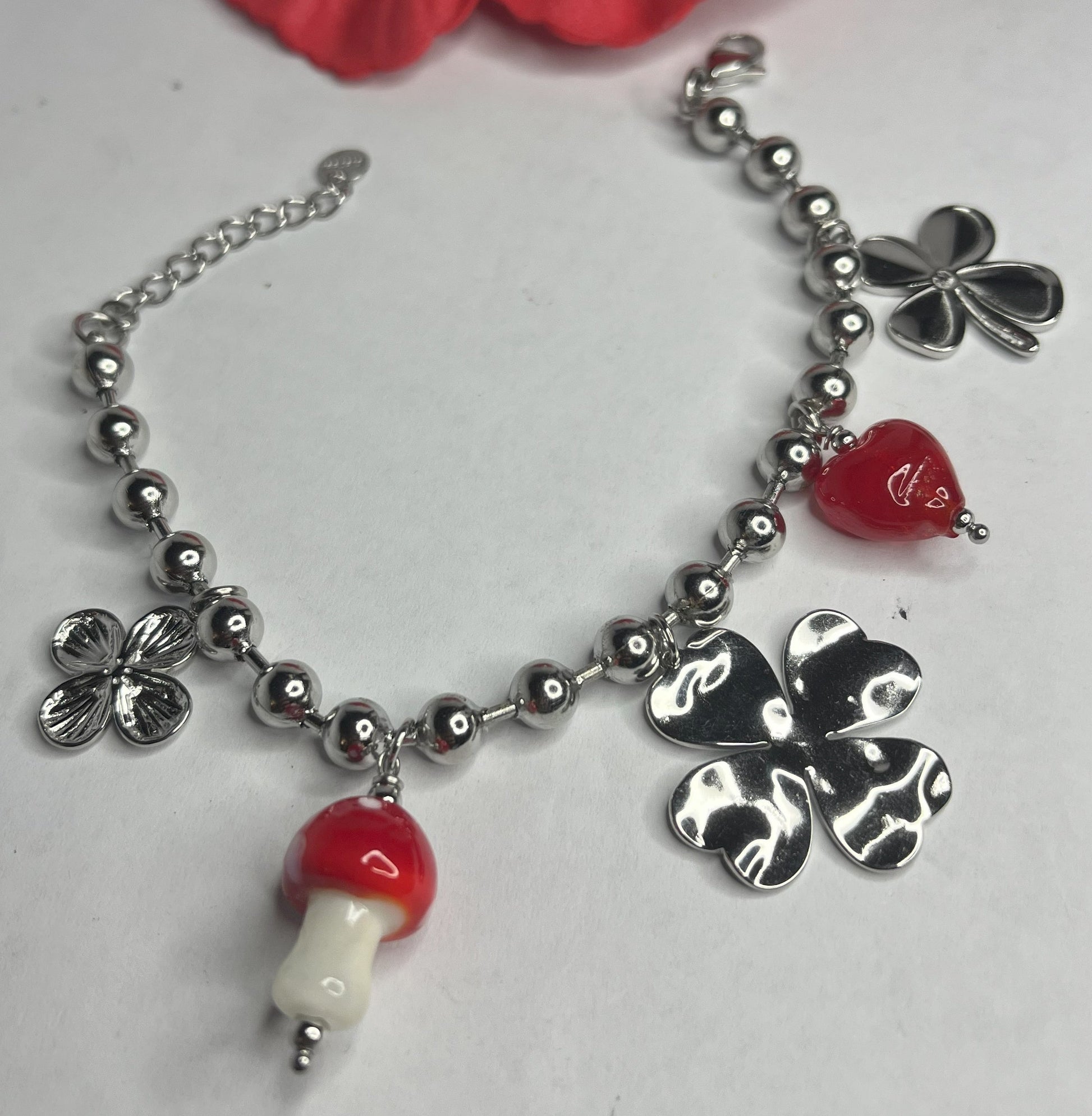 Braccialetto Giardino Magico in acciaio inox argentato con charms floreali, cuori rossi e perline colorate su sfondo grigio