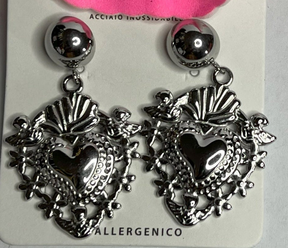 Orecchini dorati a forma di sacro cuore con dettagli intarsiati e lavorazione artigianale su sfondo con fiore rosa