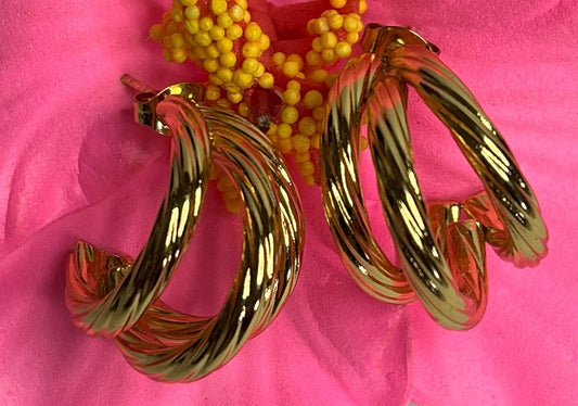 Orecchini Helix placcati oro premium con design a spirale tridimensionale, fotografati su petali di fiore rosa fucsia