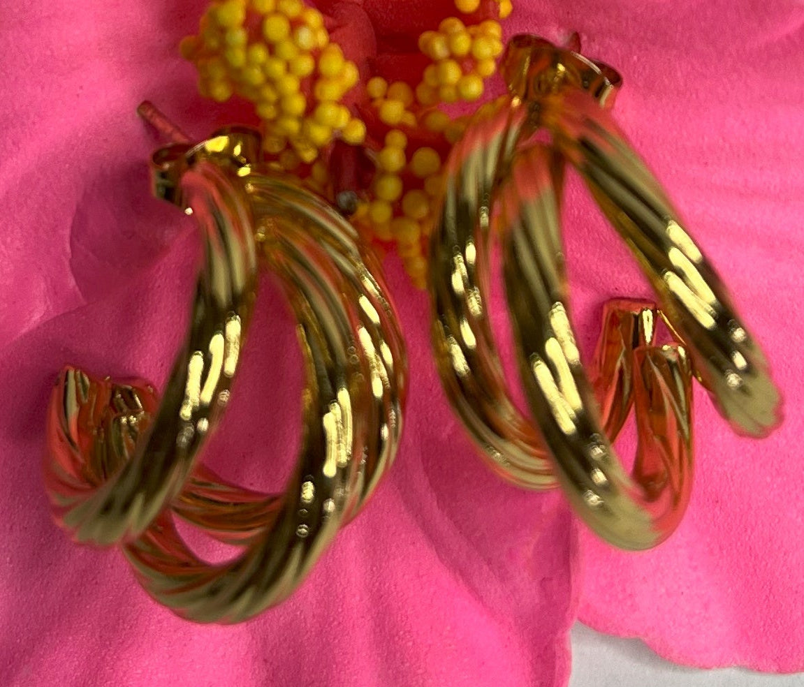 Orecchini Helix placcati oro premium con design a spirale tridimensionale, fotografati su petali di fiore rosa fucsia