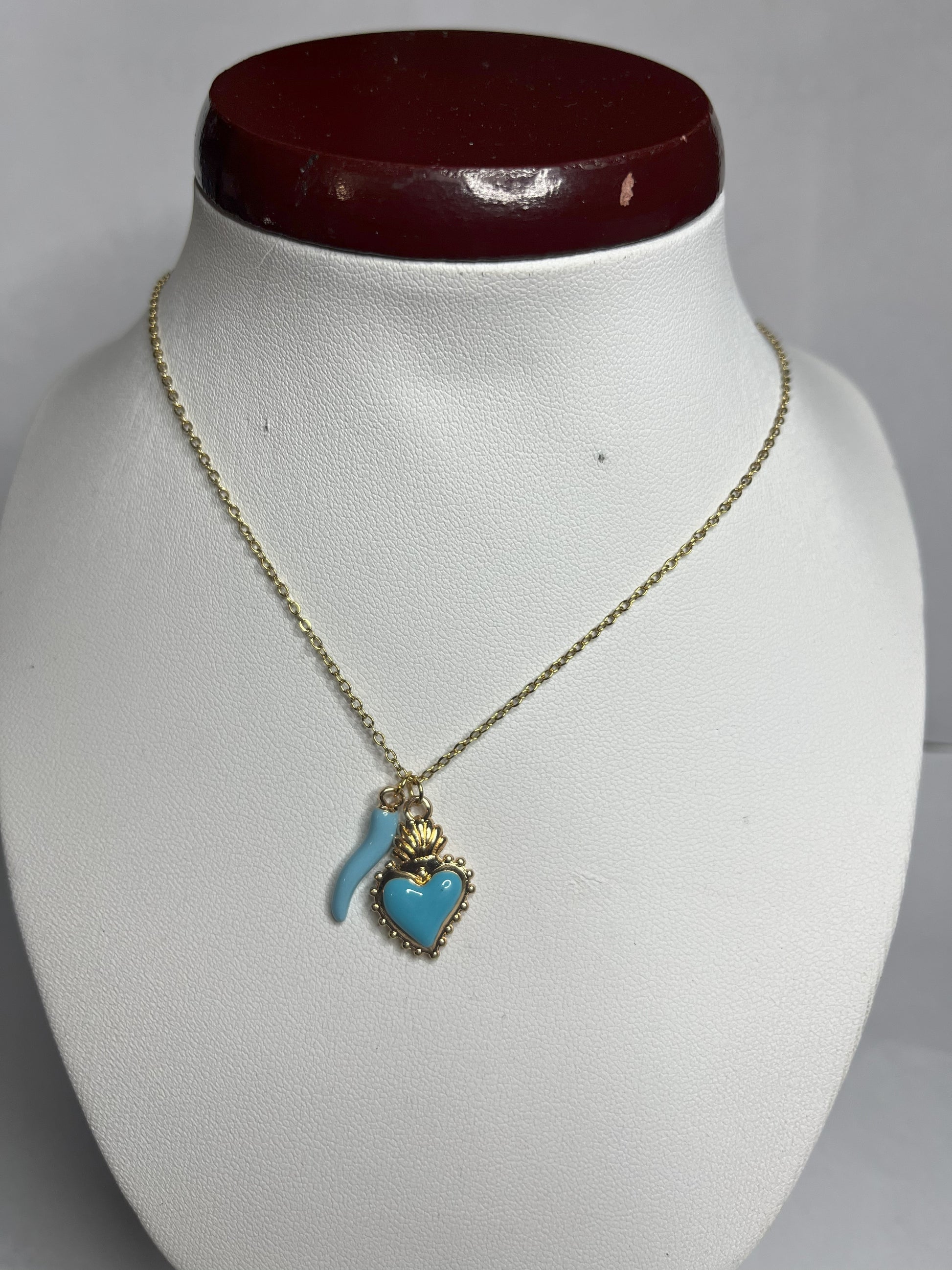 Collana Love Charm con catena dorata e doppio pendente a forma di cuore e cornetto portafortuna, disponibile in vari colori