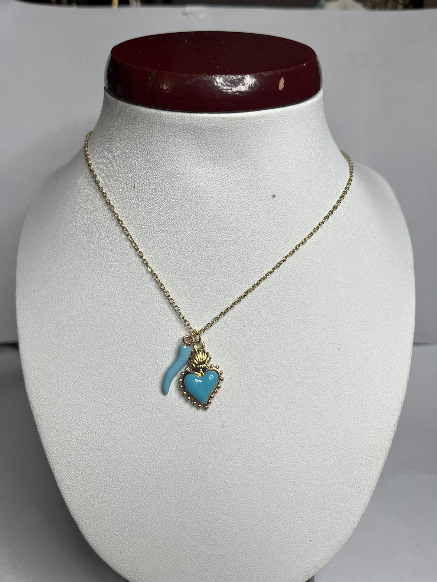 Collana Love Charm con catena dorata e doppio pendente a forma di cuore e cornetto portafortuna, disponibile in vari colori