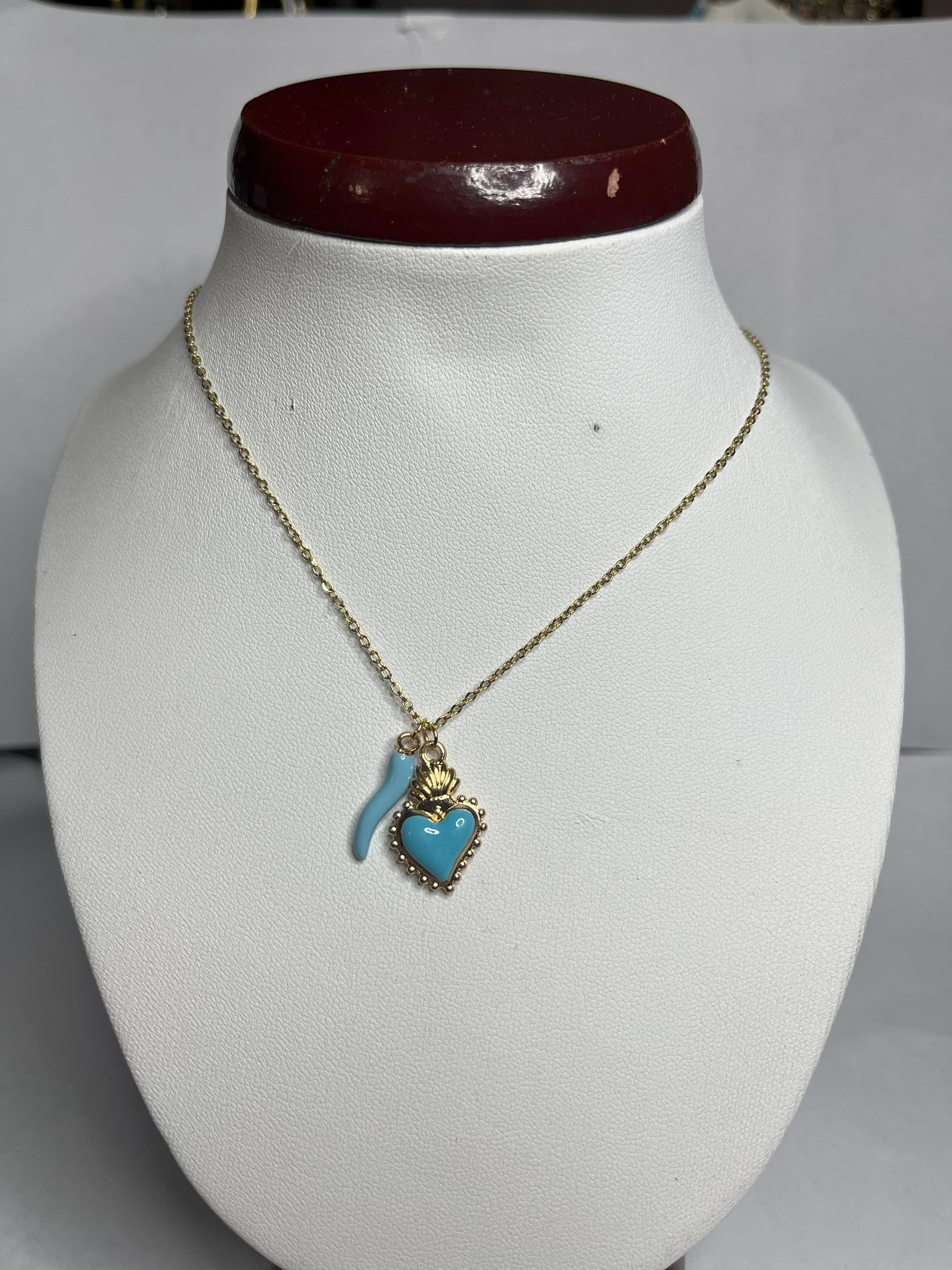 Collana Love Charm con catena dorata e doppio pendente a forma di cuore e cornetto portafortuna, disponibile in vari colori