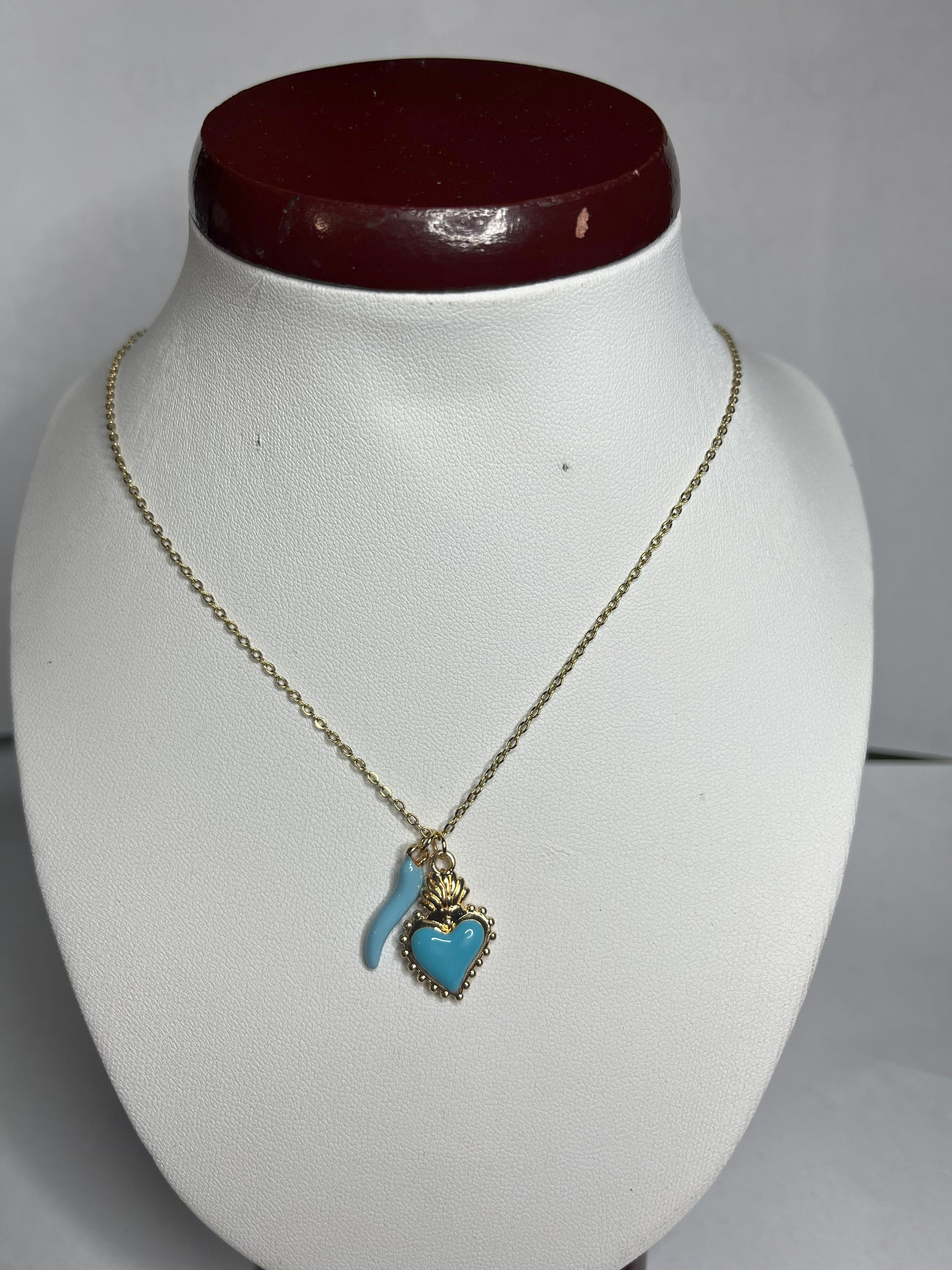 Collana Love Charm con catena dorata e doppio pendente a forma di cuore e cornetto portafortuna, disponibile in vari colori
