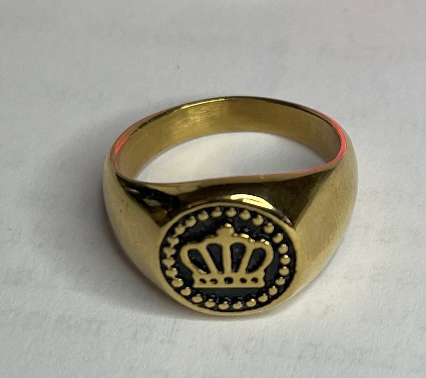 Anello Mignolo Regina in acciaio premium con design regale inciso, variante placcato oro, fotografato su superficie bianca con fiore rosa
