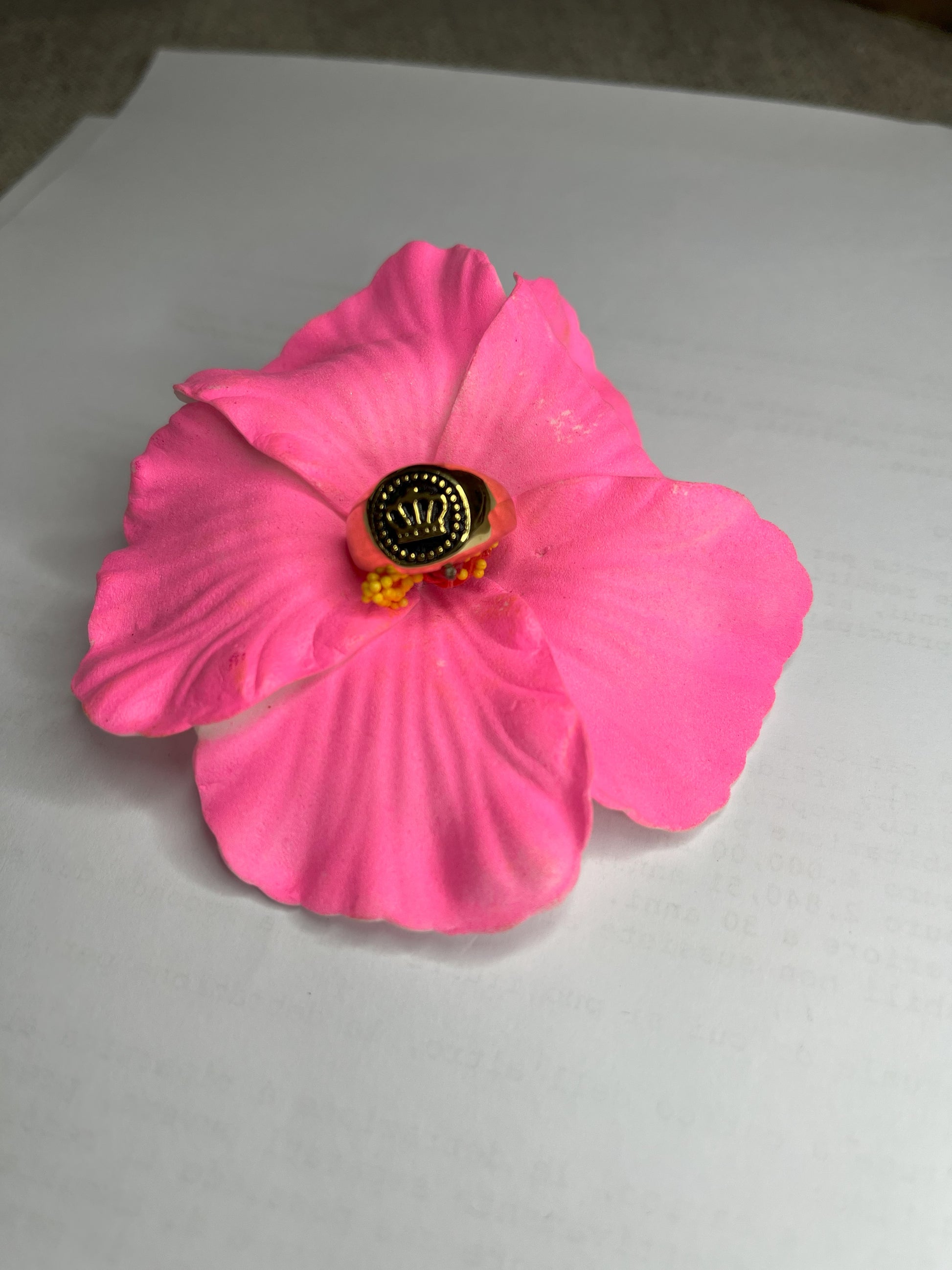 Anello Mignolo Regina in acciaio premium con design regale inciso, variante placcato oro, fotografato su superficie bianca con fiore rosa