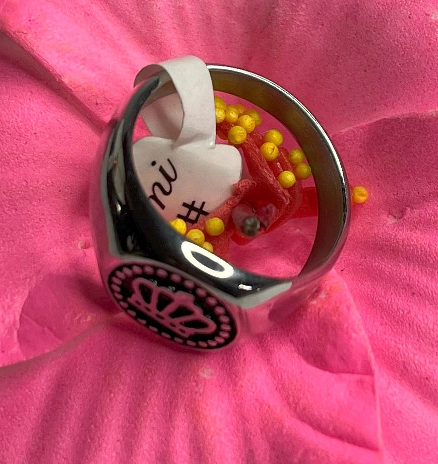 Anello Mignolo Regina in acciaio premium con design regale inciso, variante placcato oro, fotografato su superficie bianca con fiore rosa